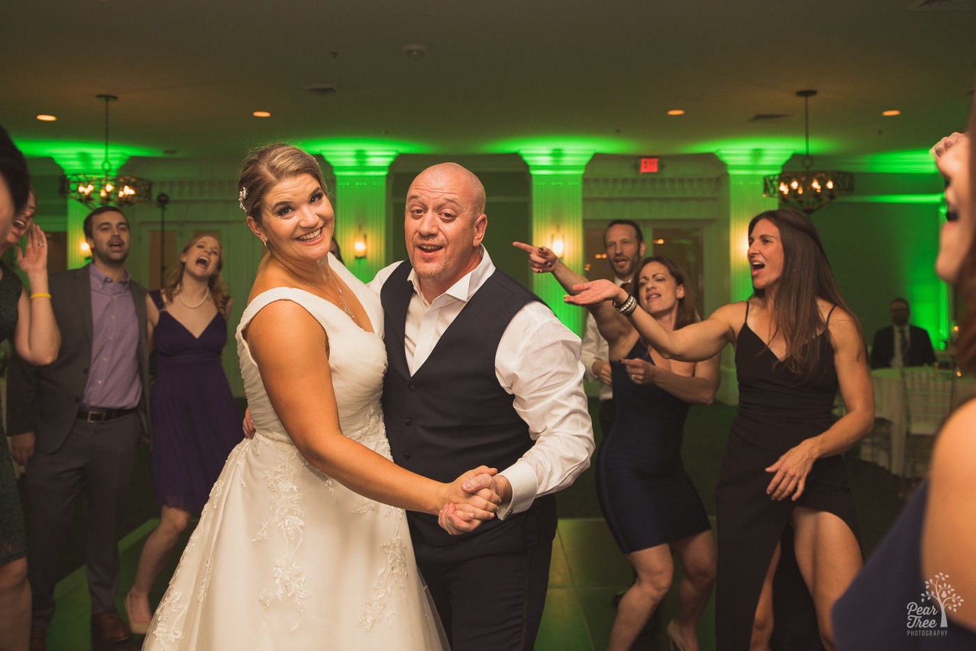 Bride and groom singing and smiling on the Cumming Polo Fields dance floor surrounded by singing friends