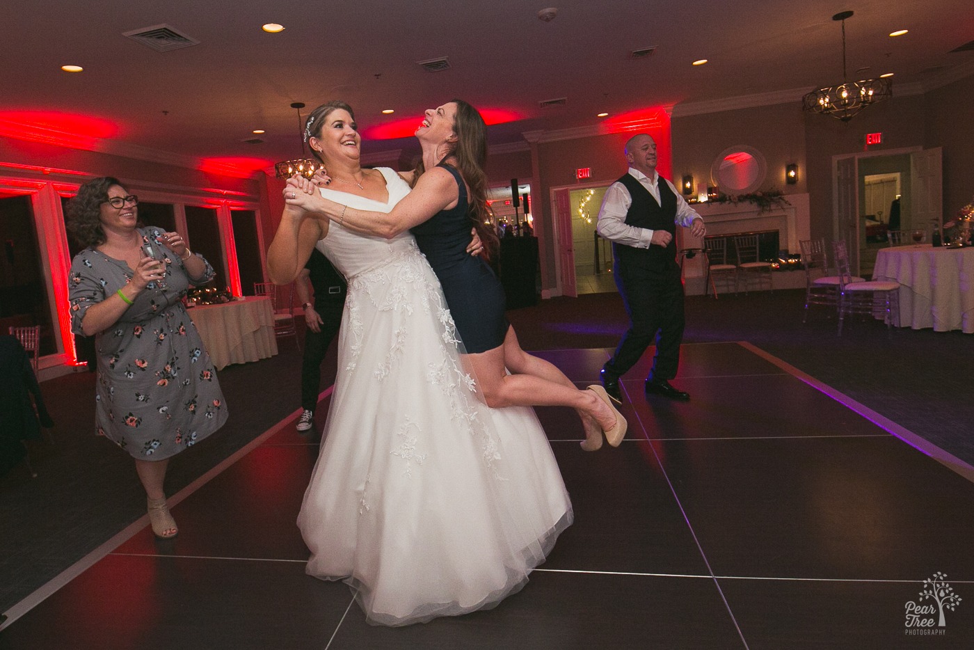 Tall bride lifting and spinning a much shorter friend around the dance floor