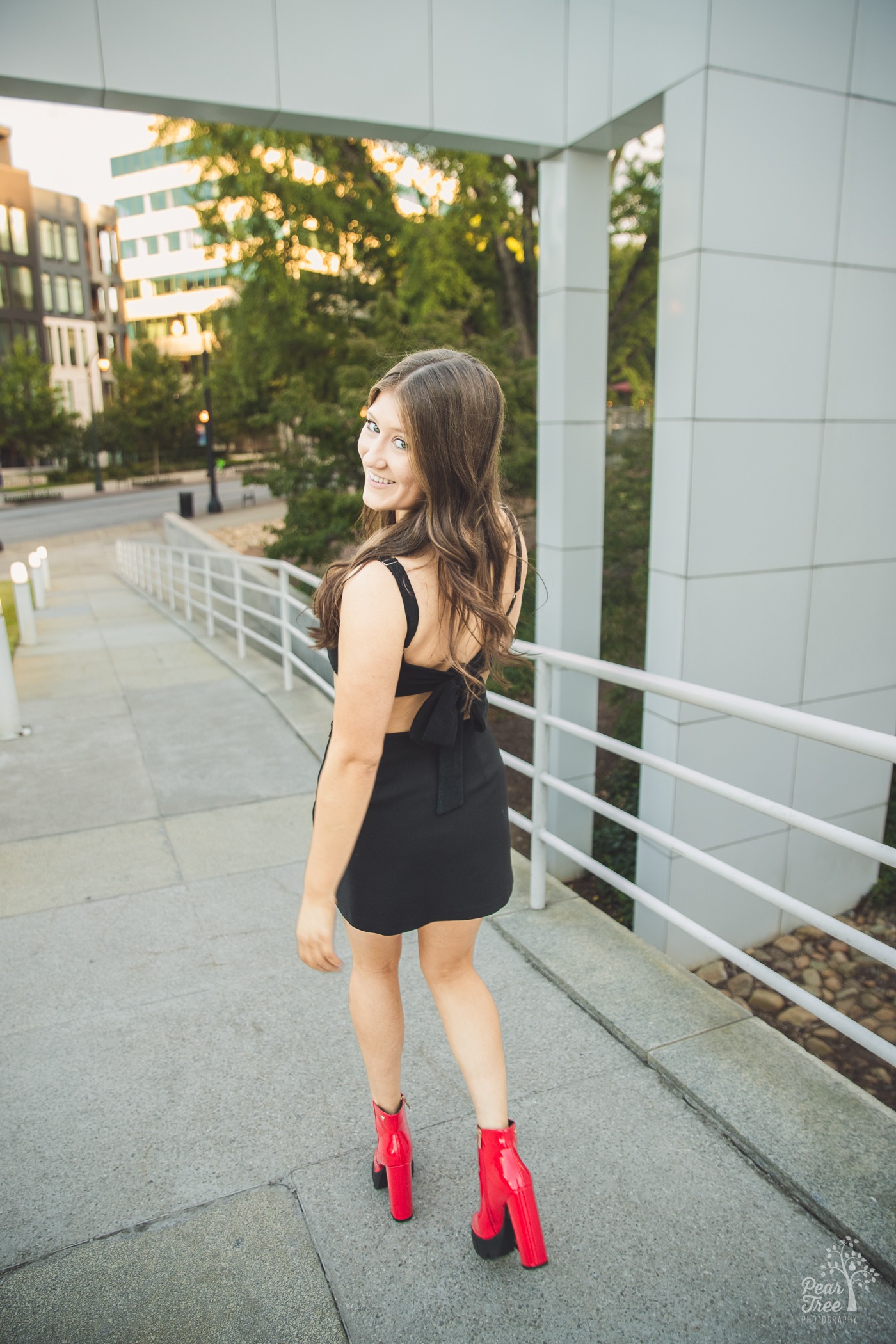 Pretty teenage girl in chunky red boots walking away from the camera while smiling over her shoulder