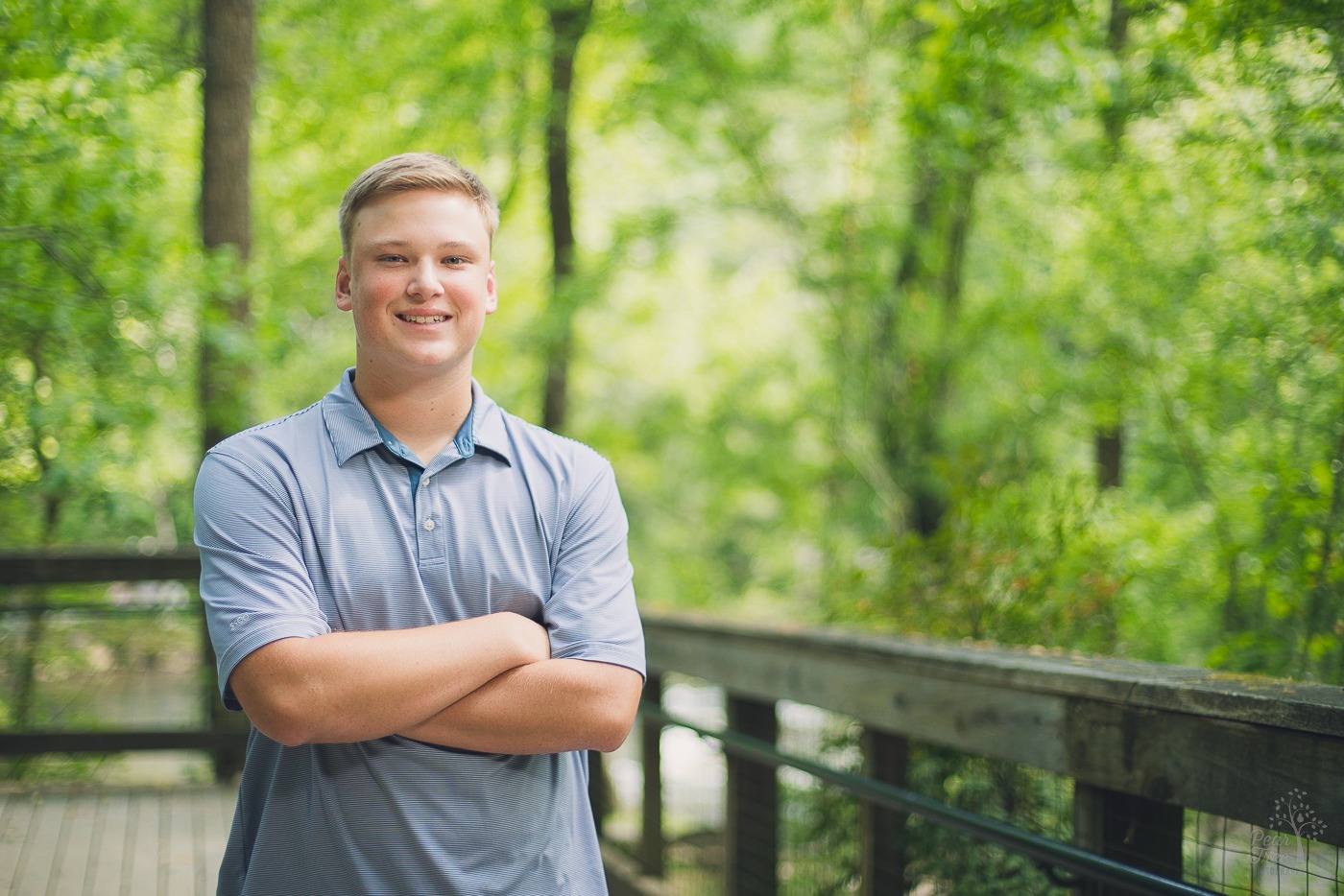 Smiling blonde teenage boy in blue shirt and crossed arms at Roswell Mill