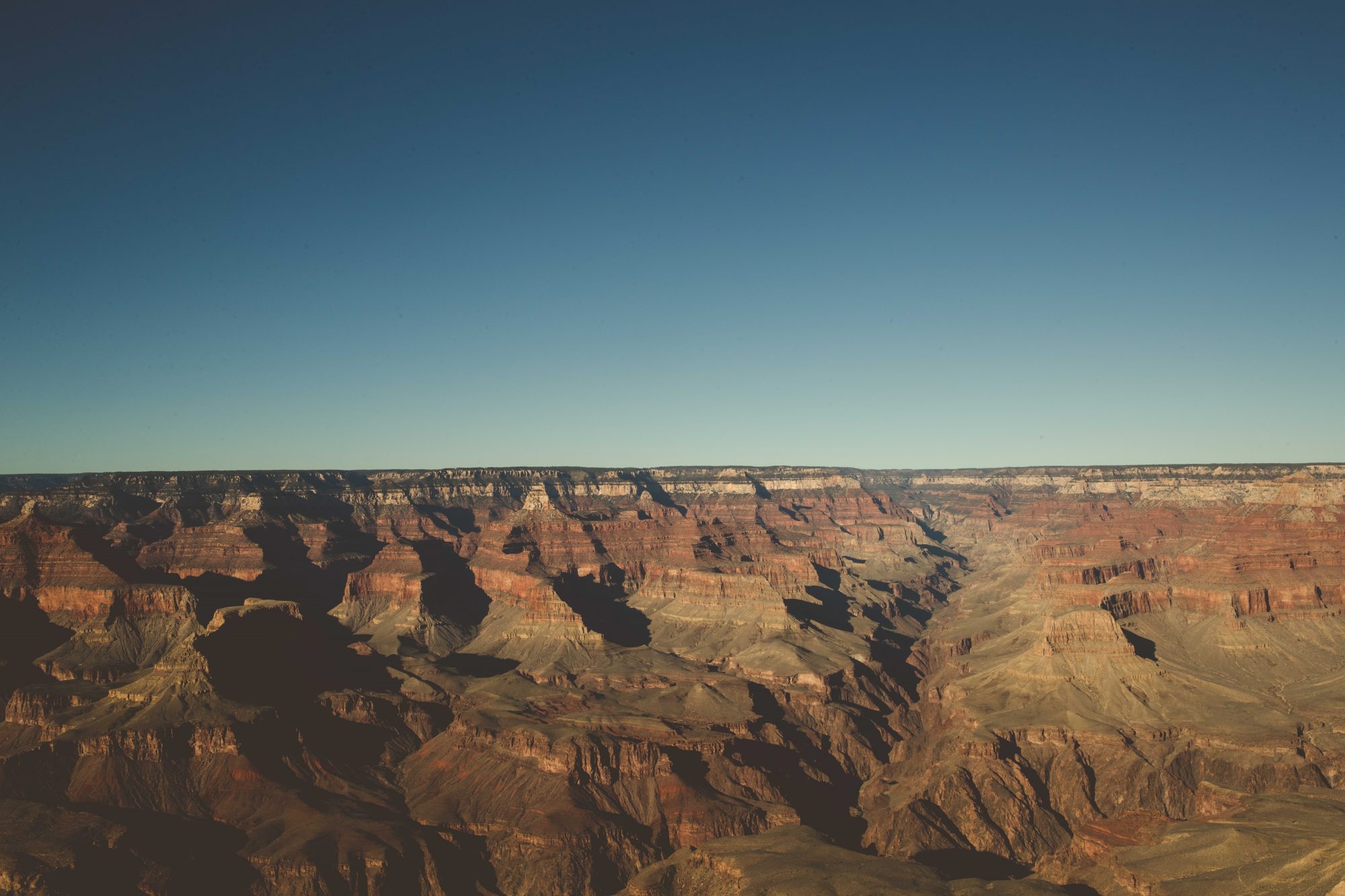 Mid afternoon view of the Grand Canyon with clear blue skies overhead