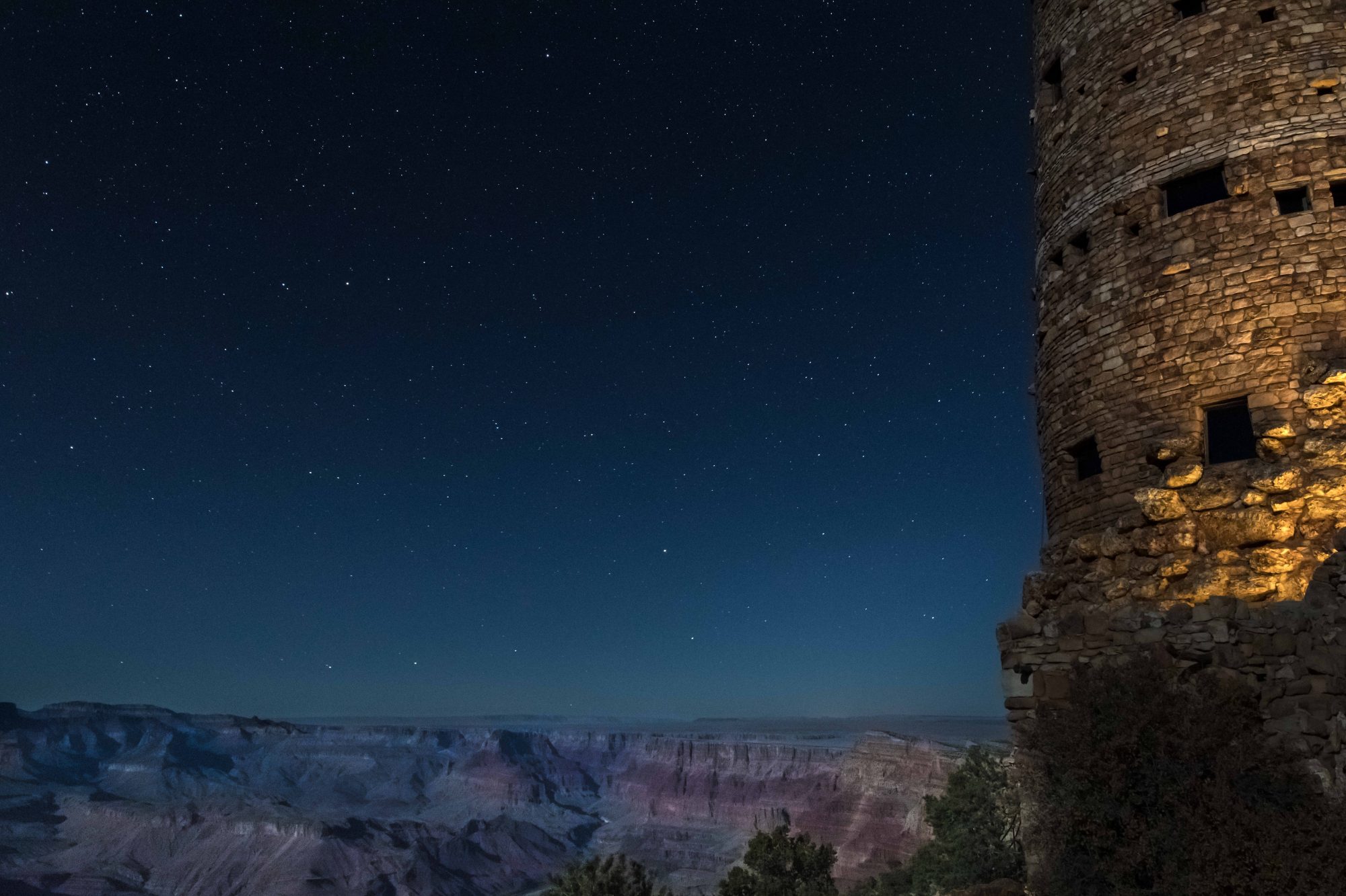 Night photograph of the Grand Canyon, the Watch Tower, and the starlit sky.