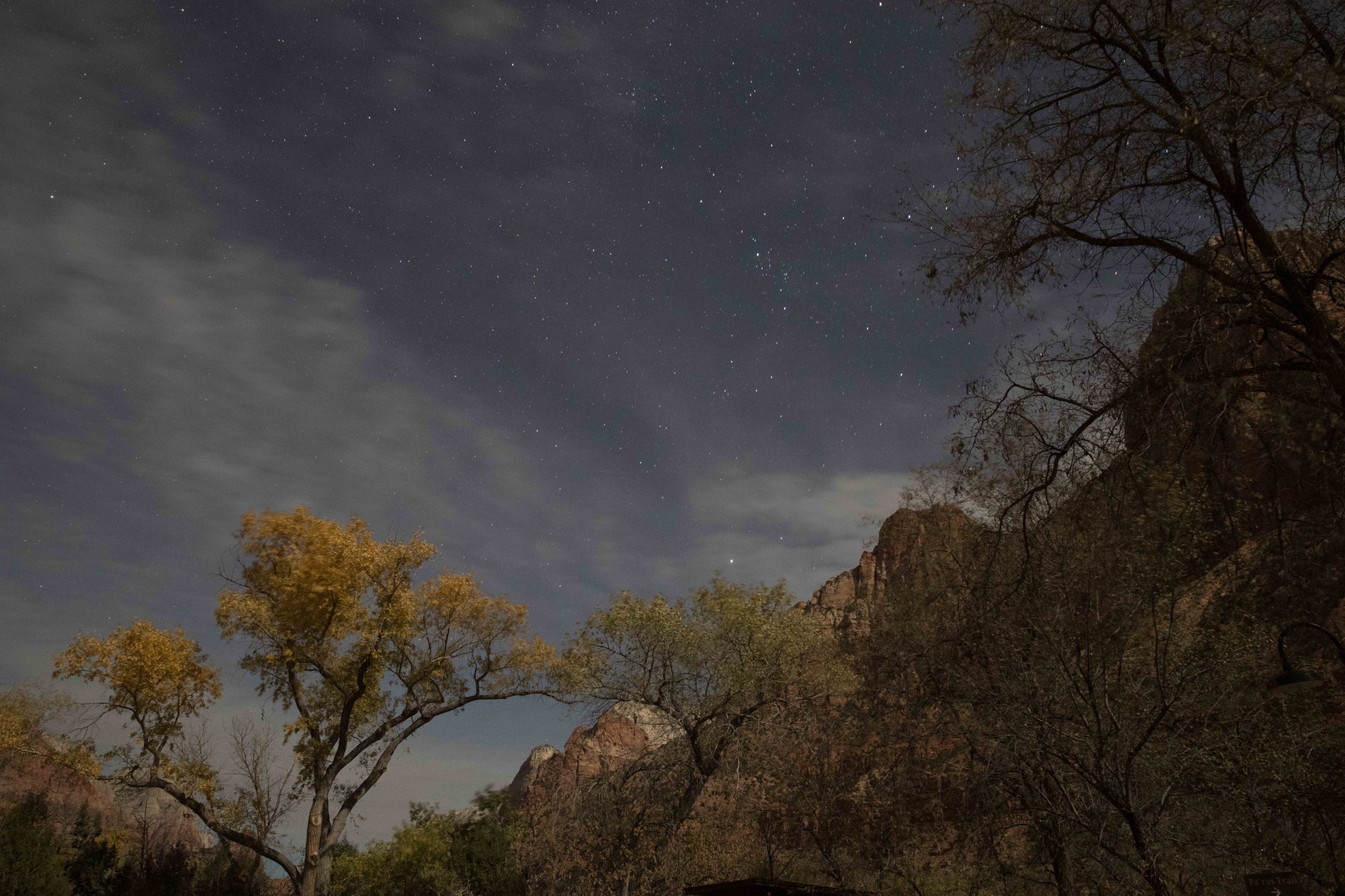 Zion National Park at night with stars shining through and above the clouds