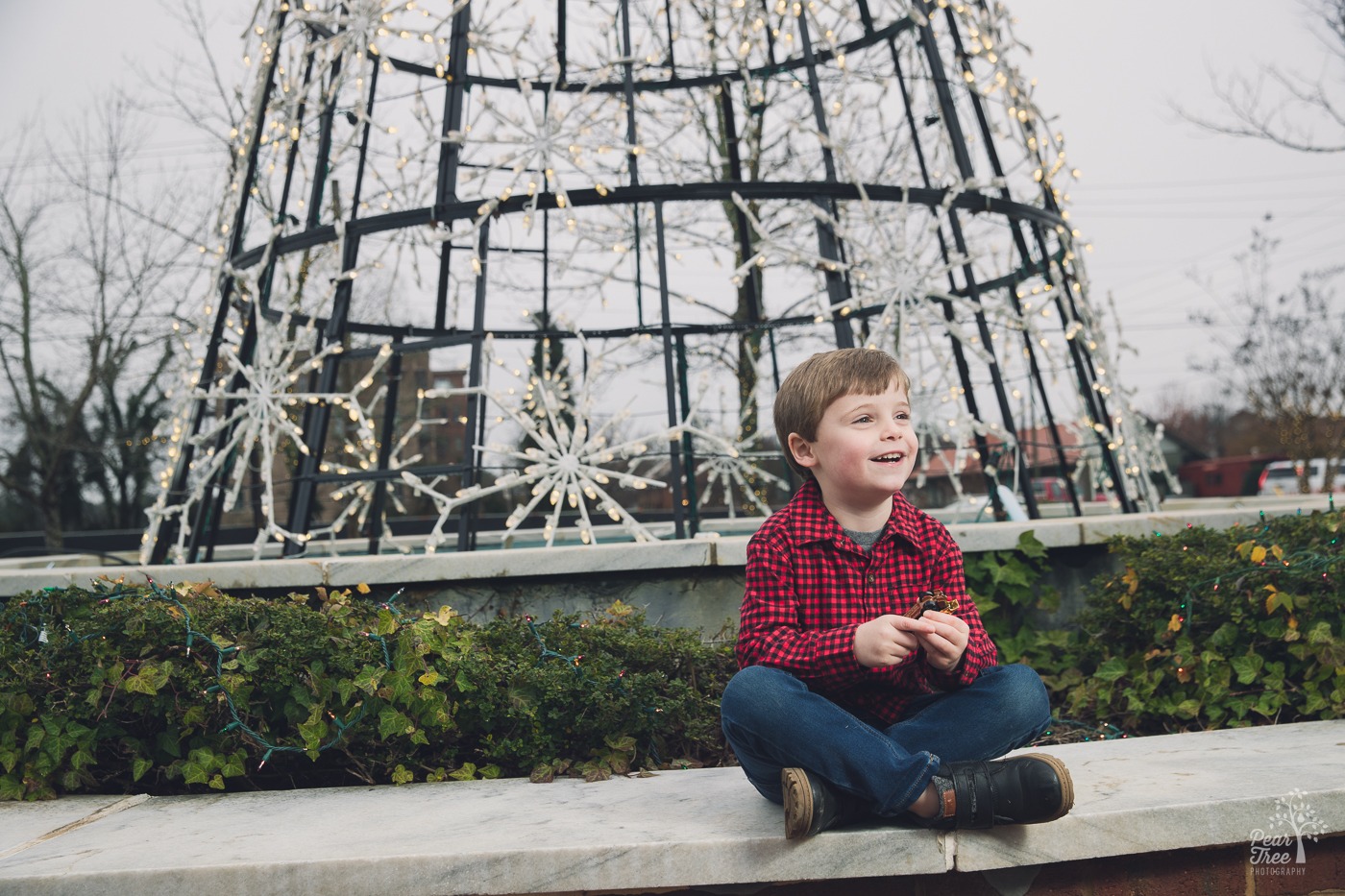Little boy smiling in front of a Christmas tree in downtown Woodstock
