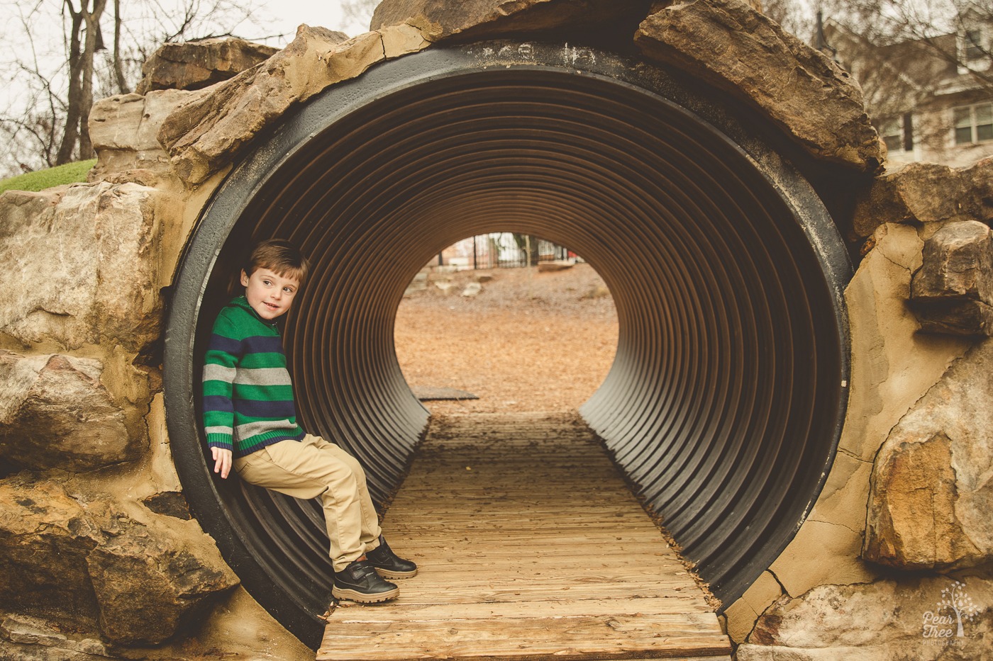 Cute little four year old boy looking out from a tunnel in downtown Woodstock and smiling