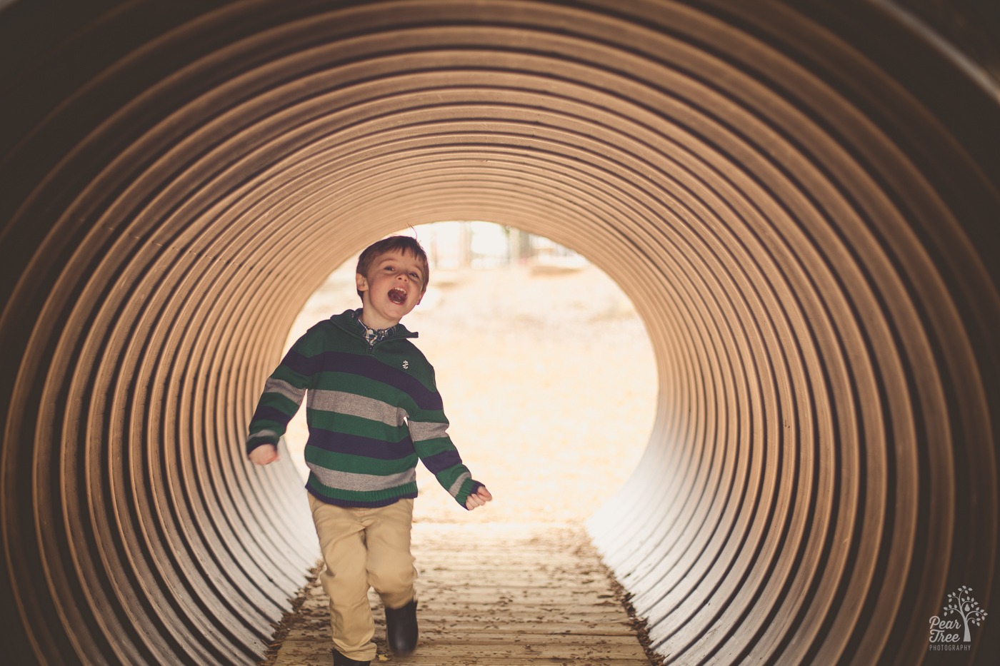 Little boy running through a tunnel having fun with his mouth wide open
