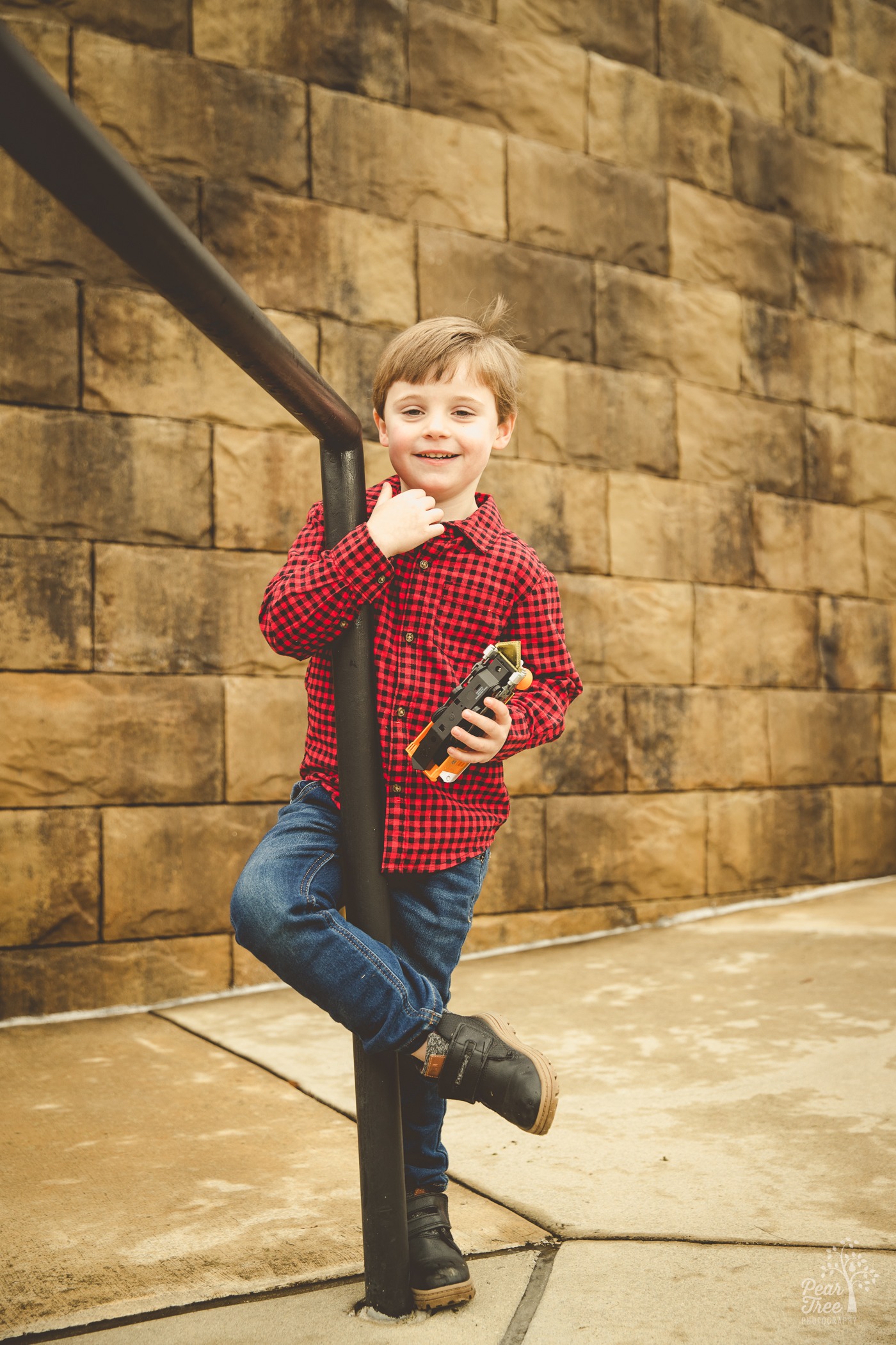 Little boy wrapping his arm and legs around a railing and smiling