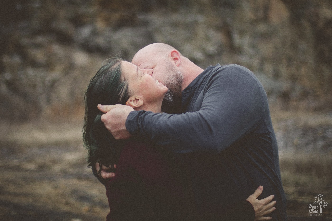 A woman smiling and laughing while her boyfriend holds her close and pulls her hair