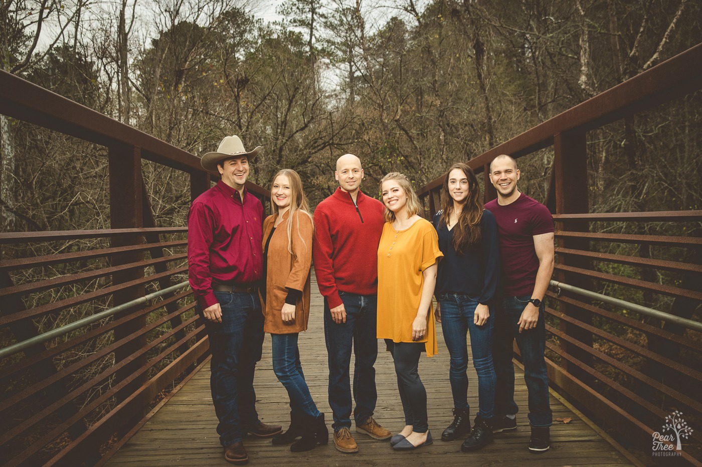 Three adult siblings standing on the Rope Mill bridge with their significant others in November