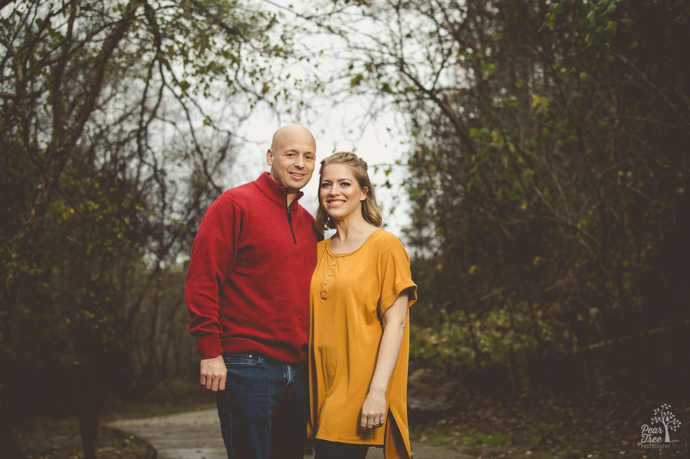 A sharply dressed couple in bold colors standing together and smiling at Rope Mill park