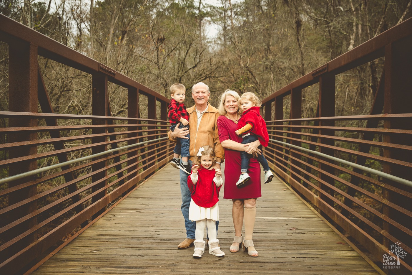 Grandparents holding their grandchildren and smiling on the Olde Rope Mill bridge in the fall