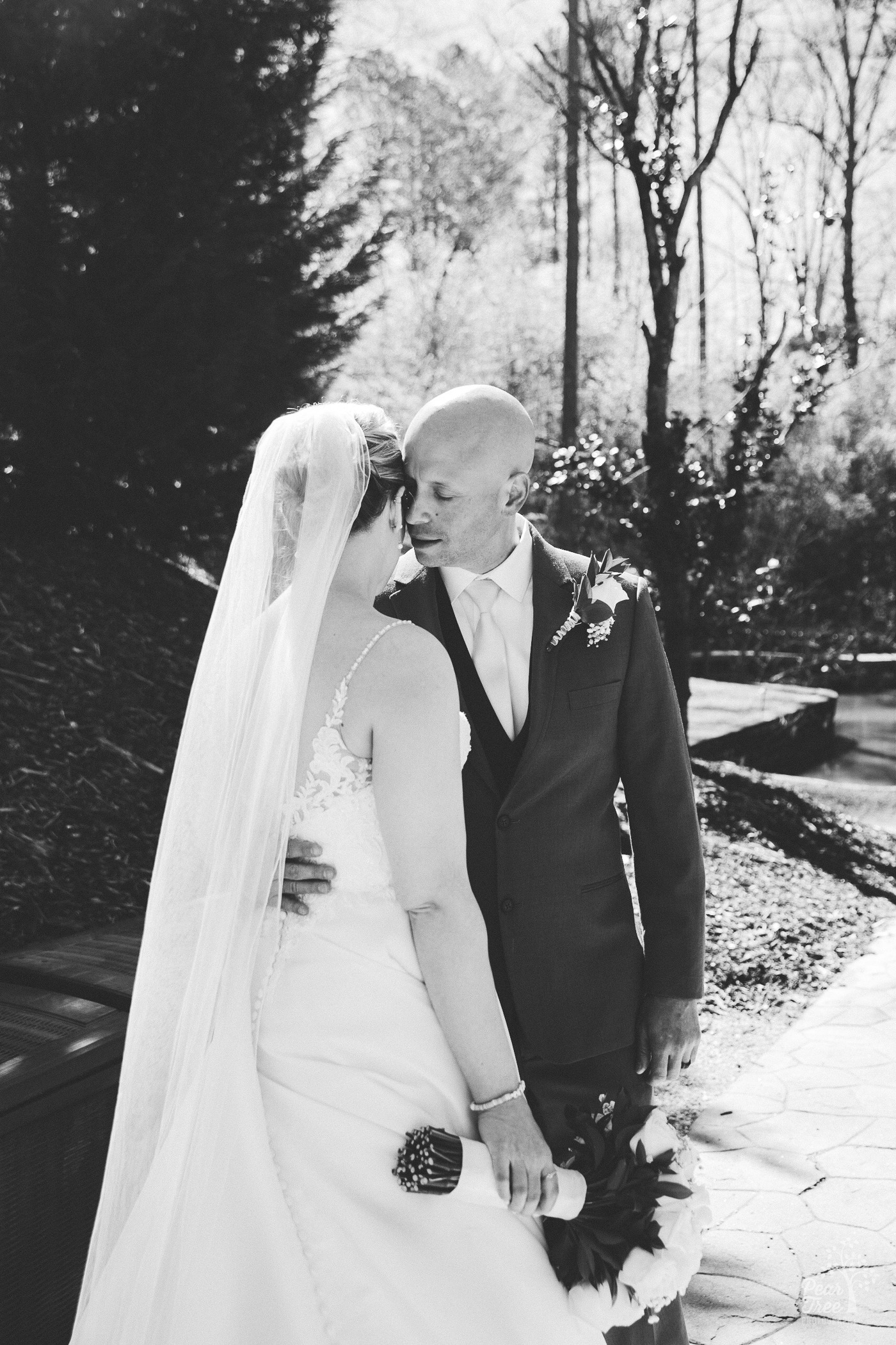 Black and white image of groom pulling his bride close and whispering in her ear