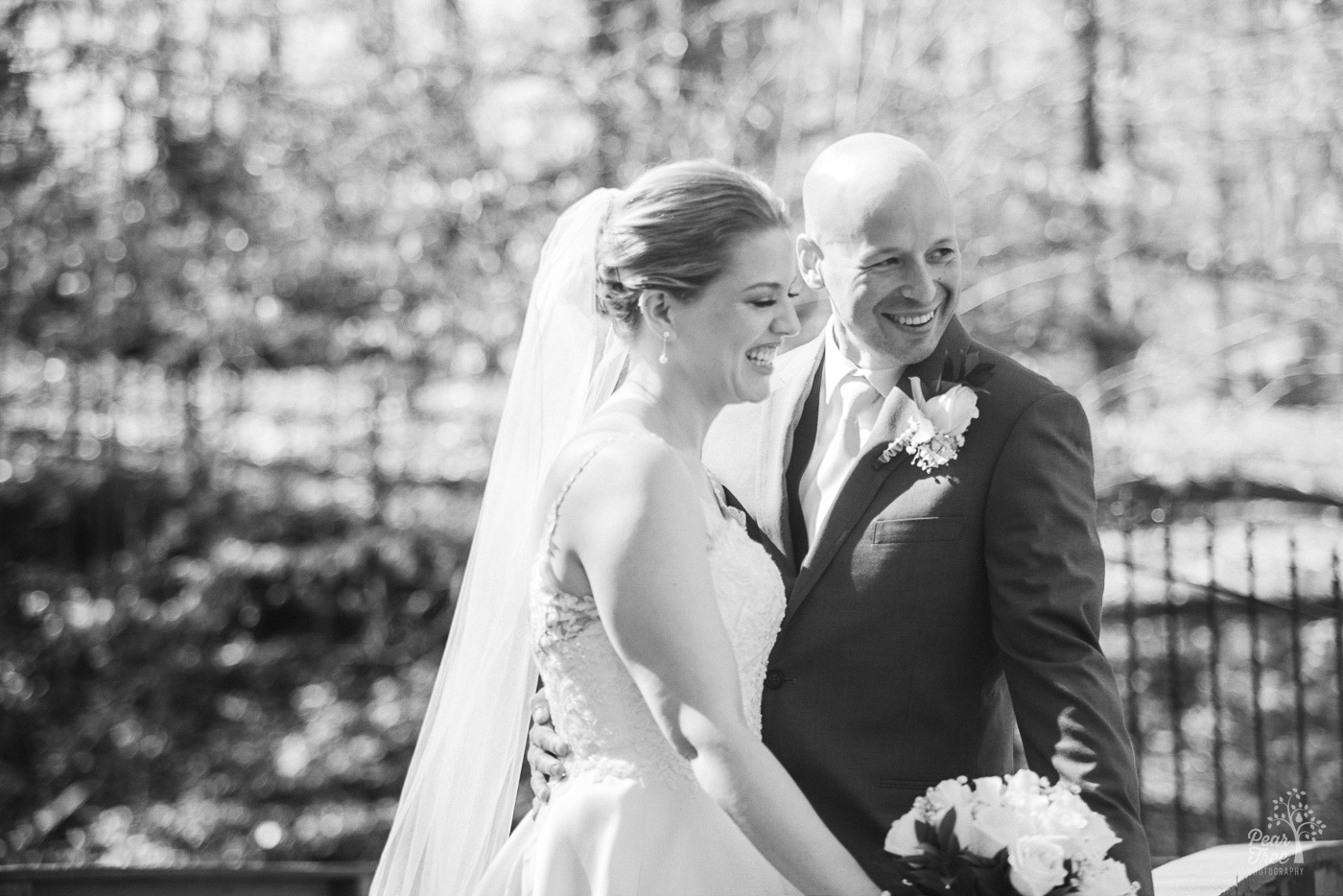 Black and white photo of bride and groom laughing while he has his hand around her back