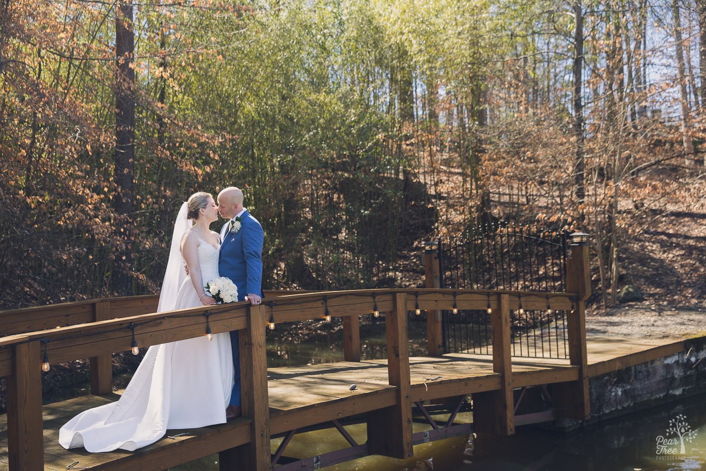 Bride and groom about to kiss on Rocky's Lake Estate foot bridge