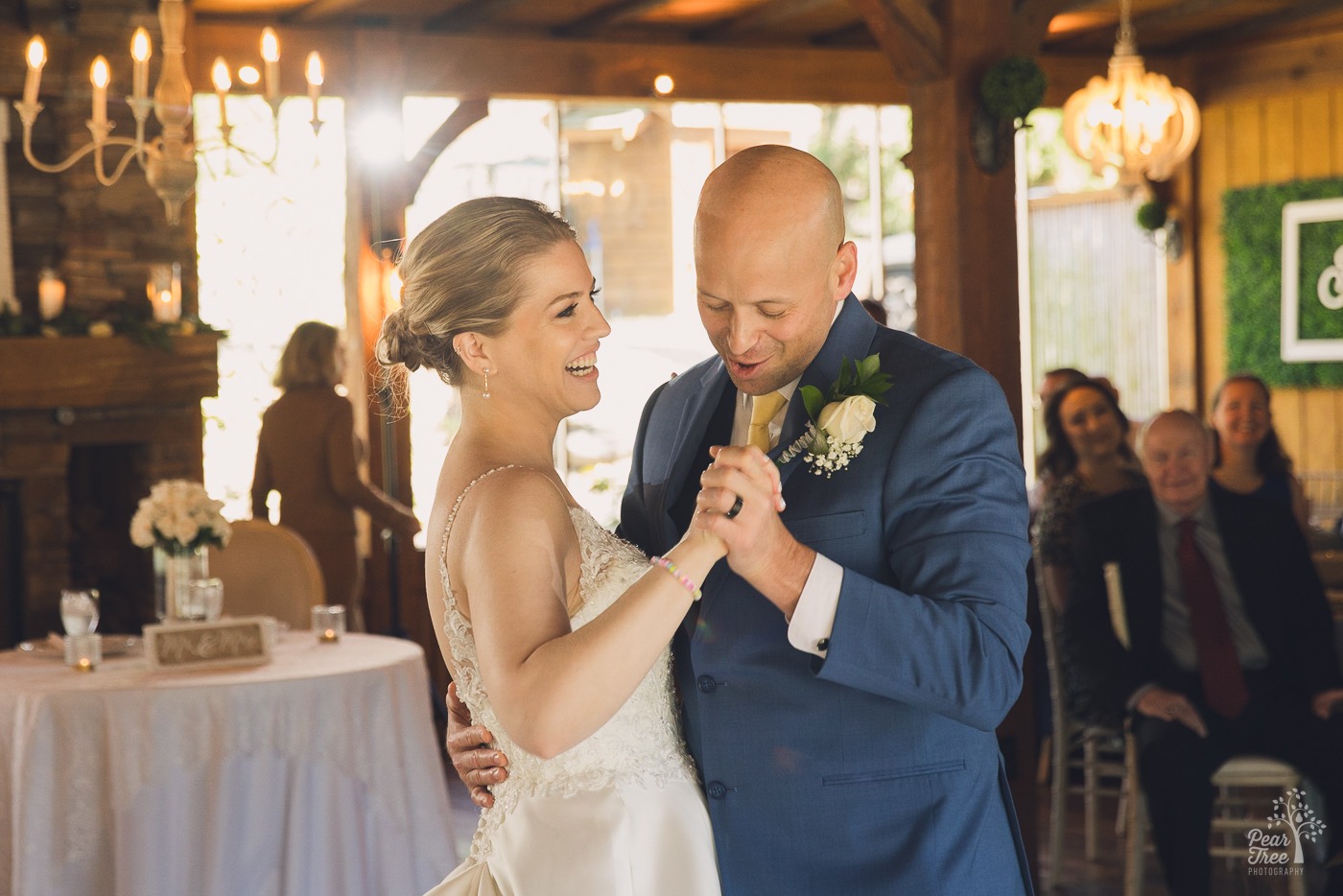 Bride laughing while her groom sings to her during their first dance