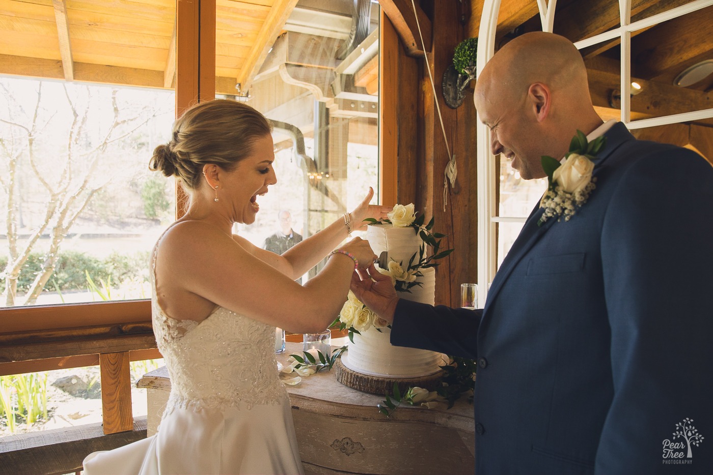 Bride making a face as she cuts the cake with her groom