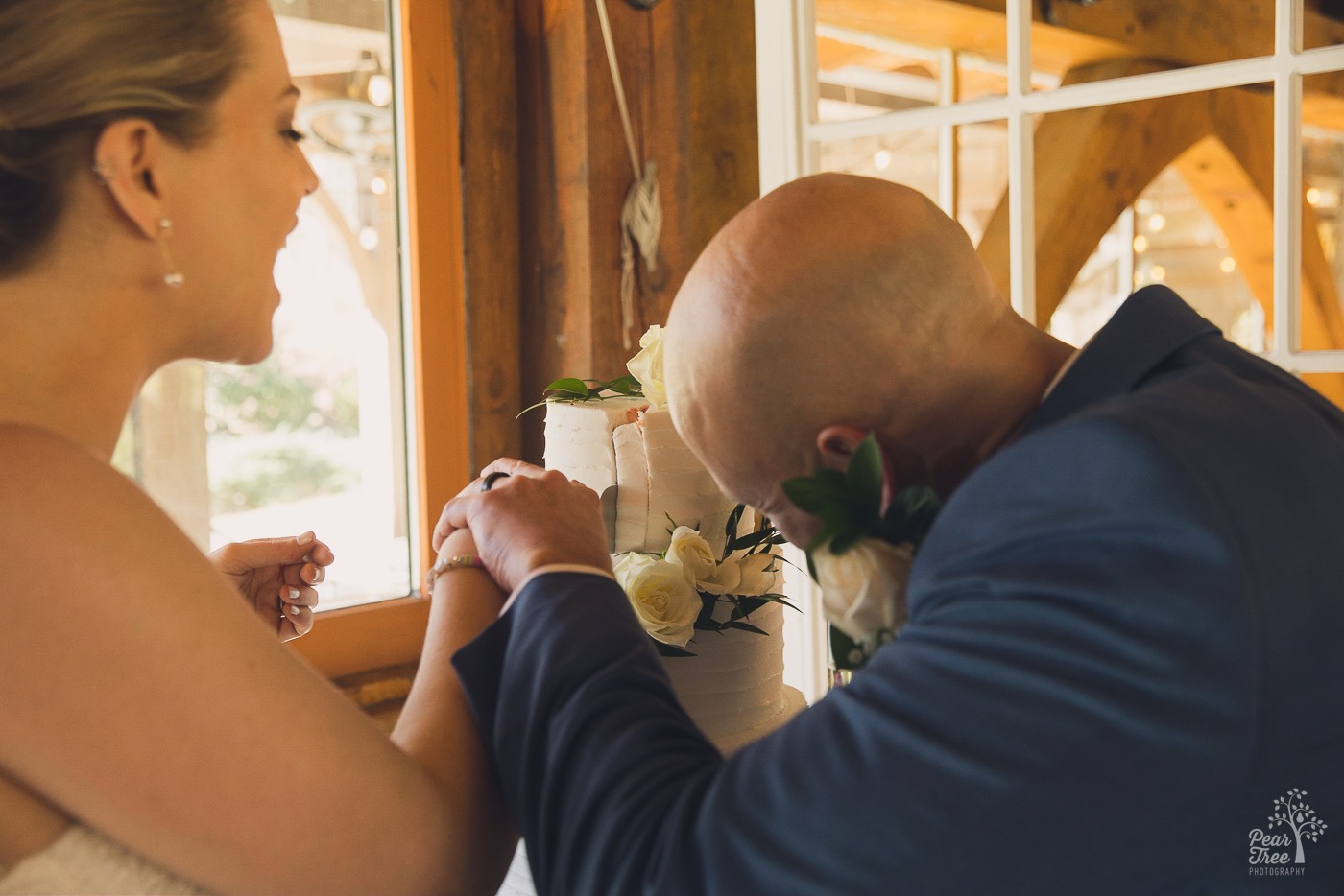 Bride and groom working together to cut their first slice of cake