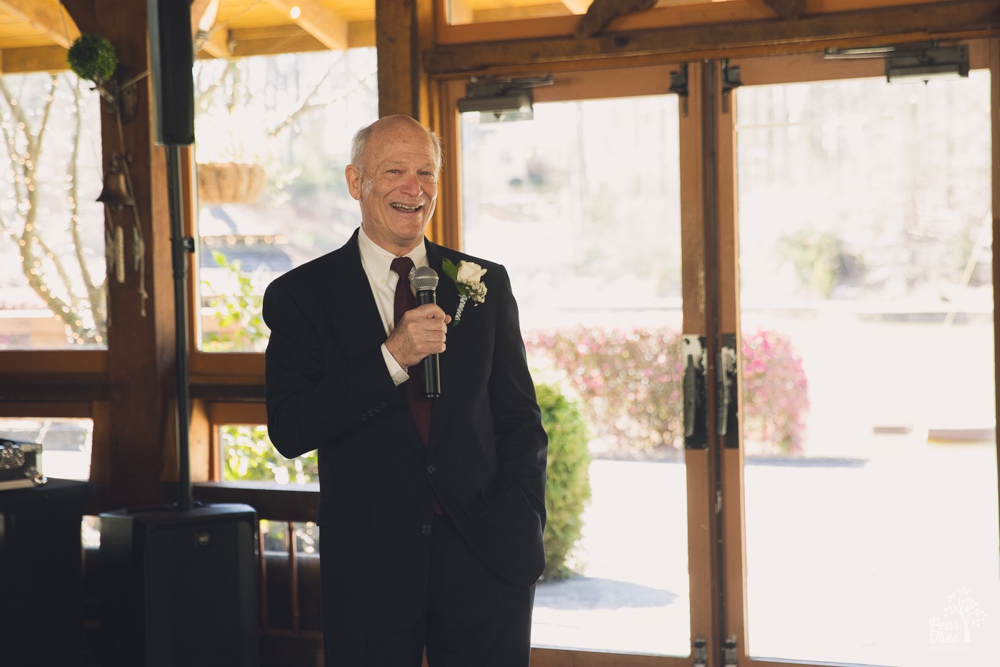 Father of the bride smiling while holding the microphone and toasting his daughter
