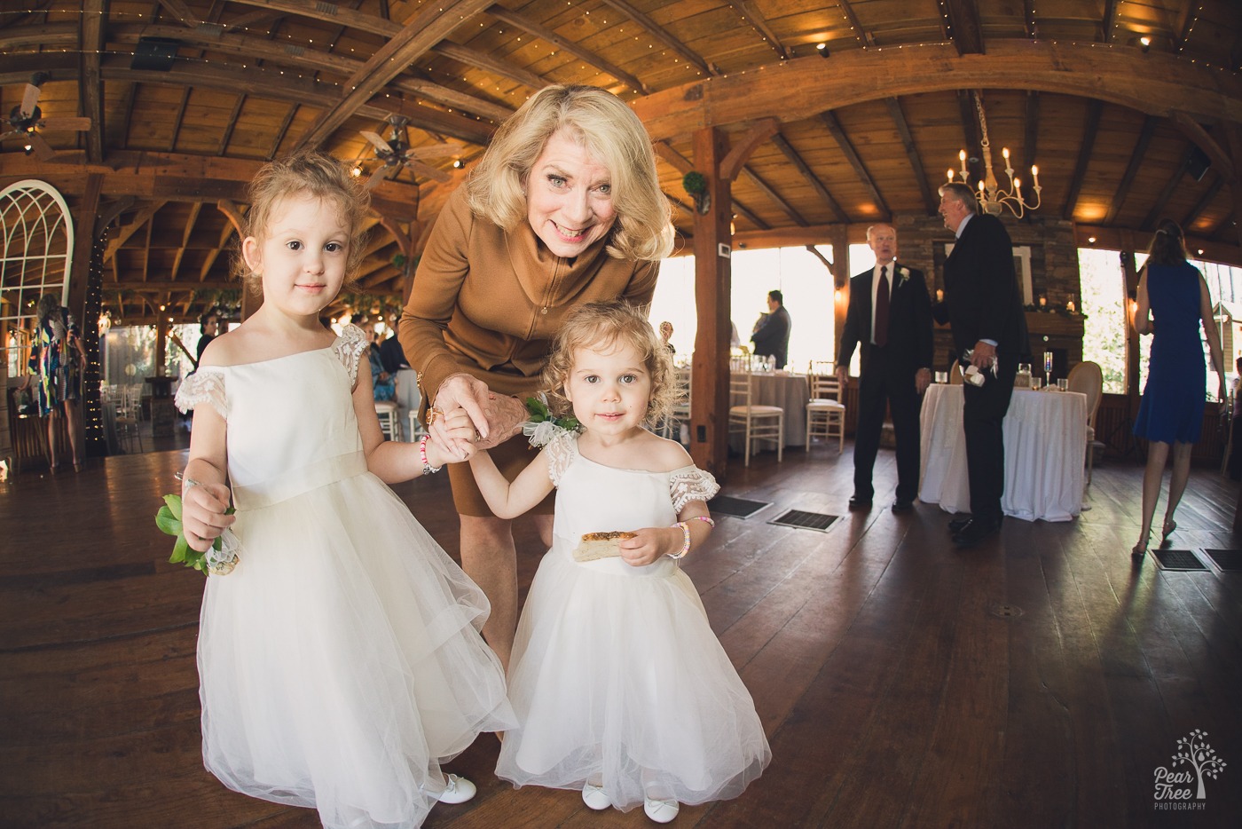 Mother of the bride holding her grand daughters' hands and smiling at wedding reception