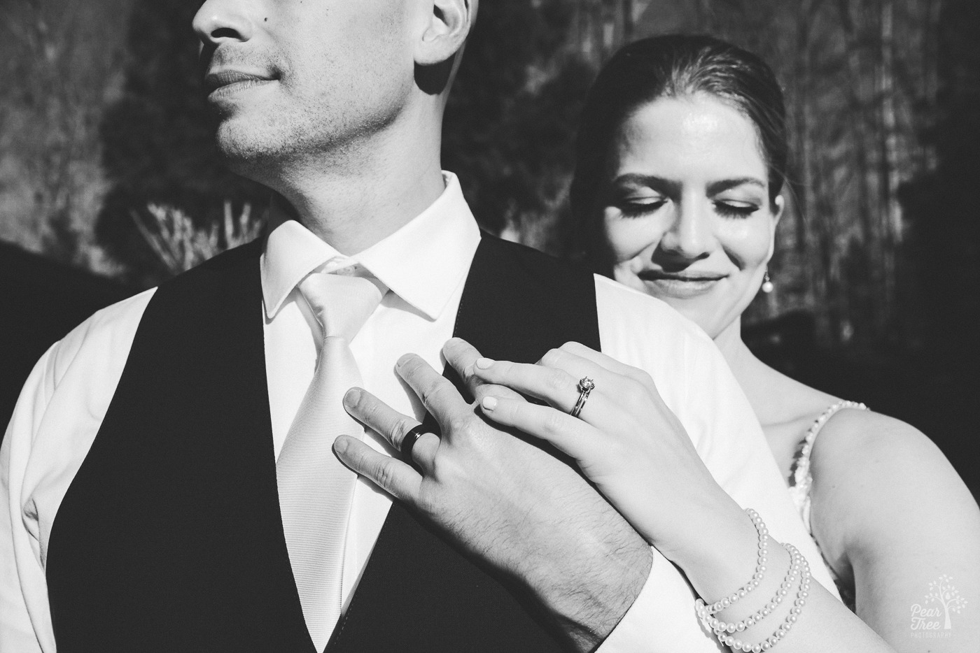 Black and white photo of bride holding her groom's hand and showing off their wedding bands