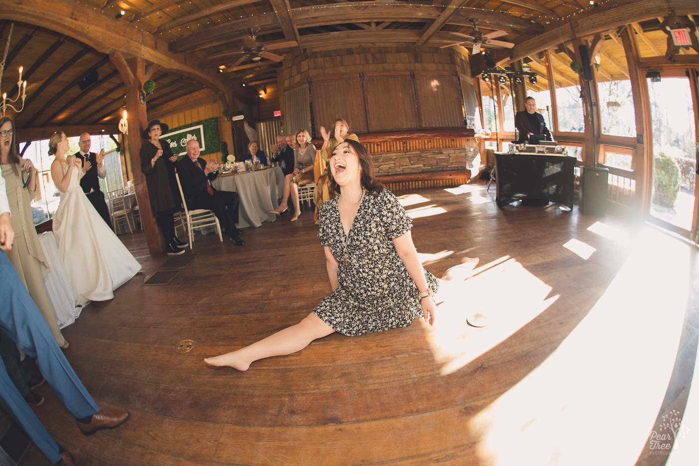 Woman doing the splits and smiling on a wedding reception dance floor