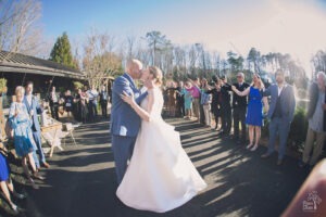 Bride and groom kissing at Rocky's Lake Estate wedding exit while guests hold sparklers