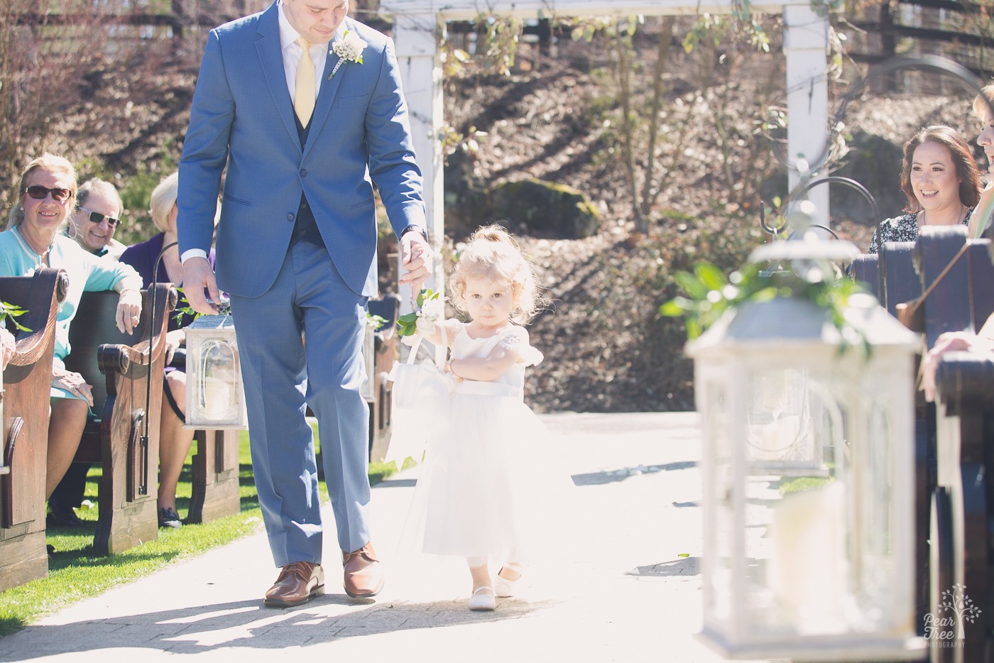 Sweet flower girl walking down the wedding aisle holding her dad's hand at Rocky's Lake Estate