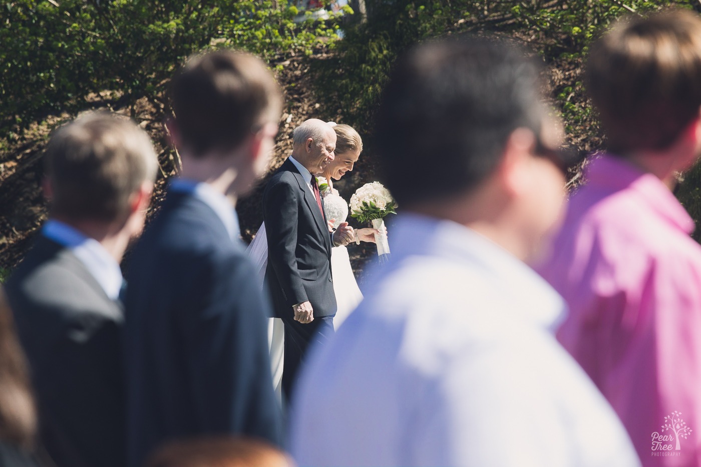 Glimpse through the crowd of guests off the father walking his daughter bride