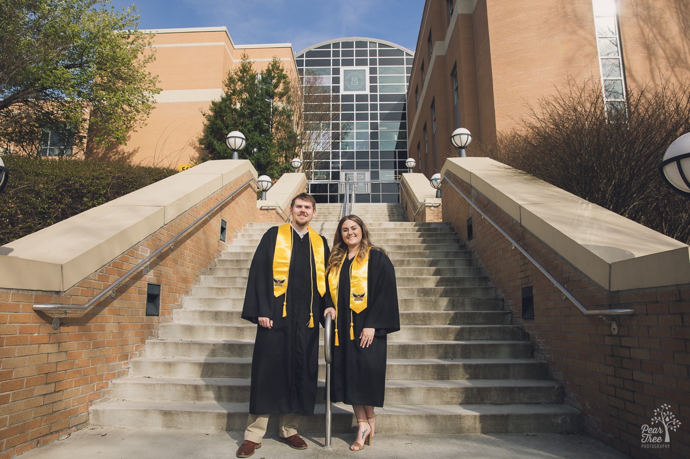 Happy graduating couple standing together smiling on steps in front of KSU business building for KSU graduation photos