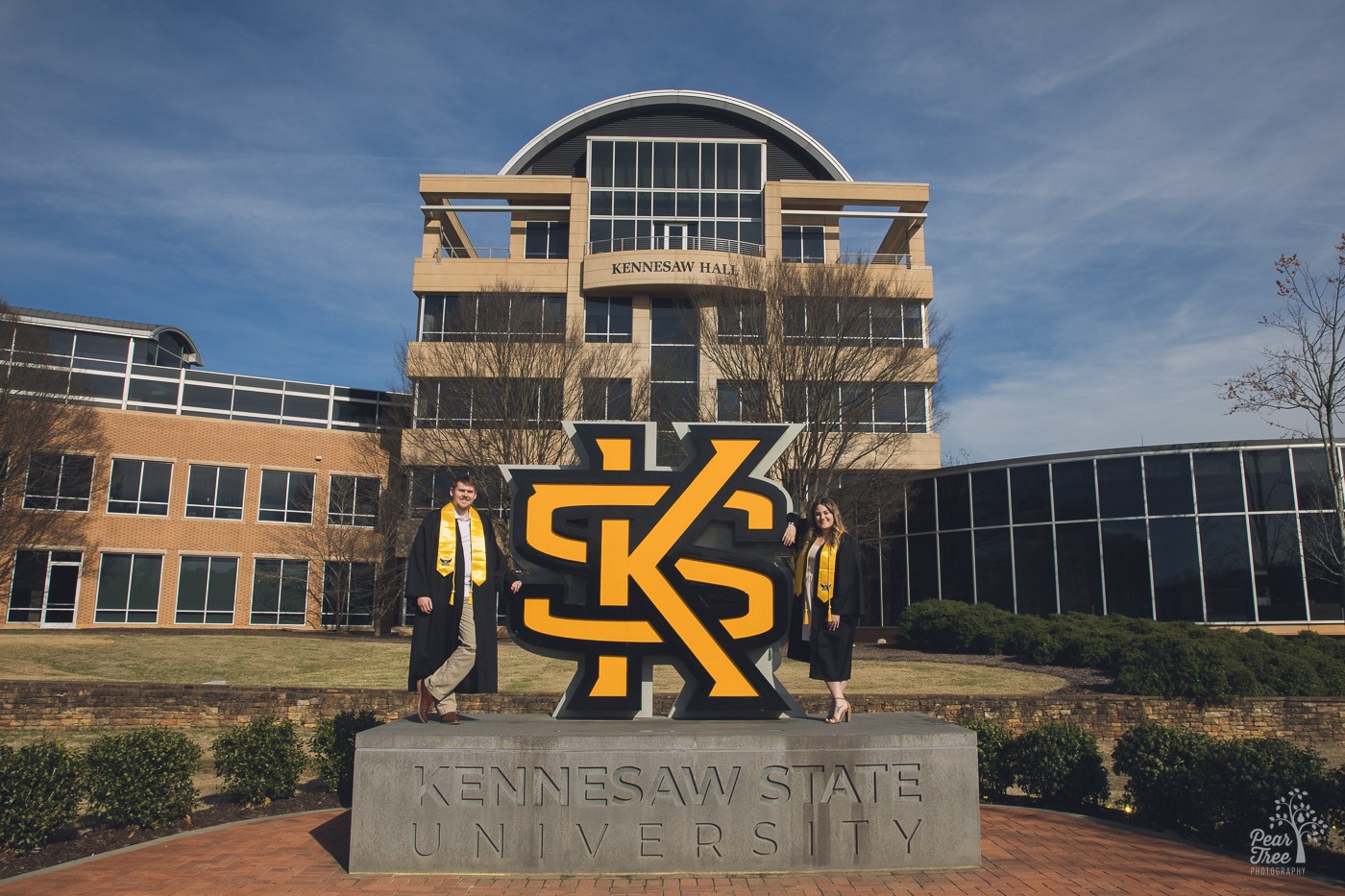 KSU graduation photos with two students standing on KSU sign