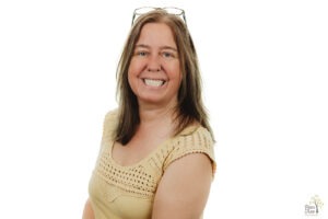 Professional headshot of a woman with glasses on her head in front of a white background during Faces of Autism project