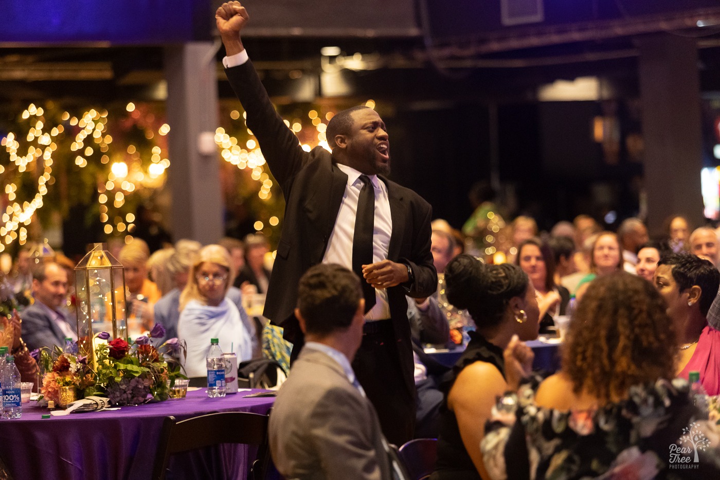 A man standing and raising his fist in the air in excitement during a Night of Broadway Stars 2023 live auction for Covenant House Georgia