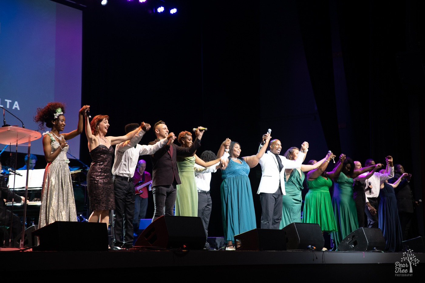 Broadway Stars and Covenant House Georgia youth holding hands above their heads and smiling as they end their singing performance