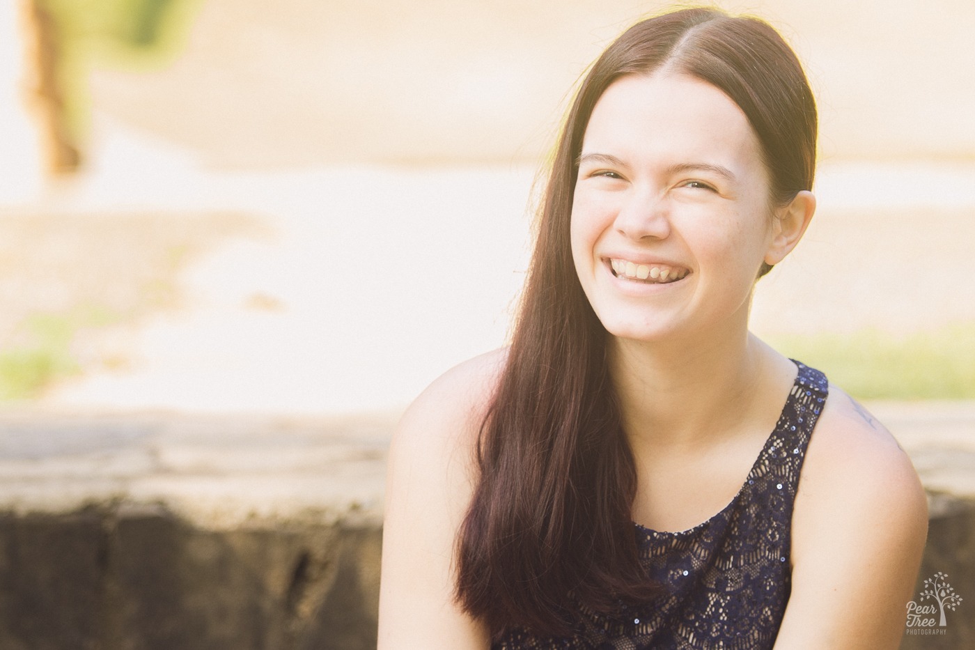 Smiling teenage girl wearing a pretty sparkling blue dress and long hair pushed to one side