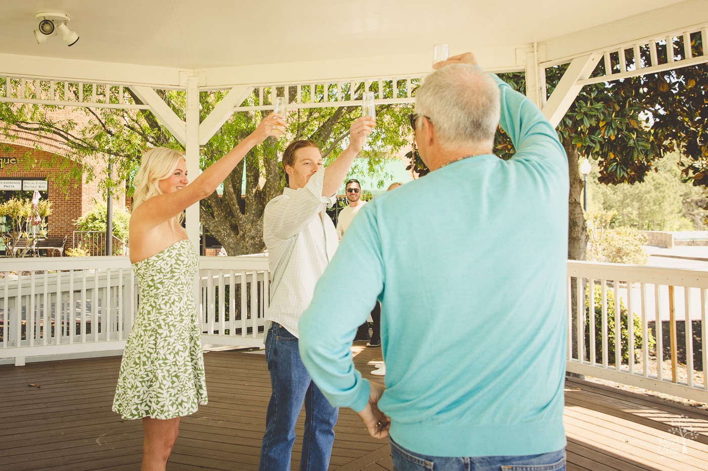 Newly engaged couple toasting champagne with family in the Woodstock gazebo