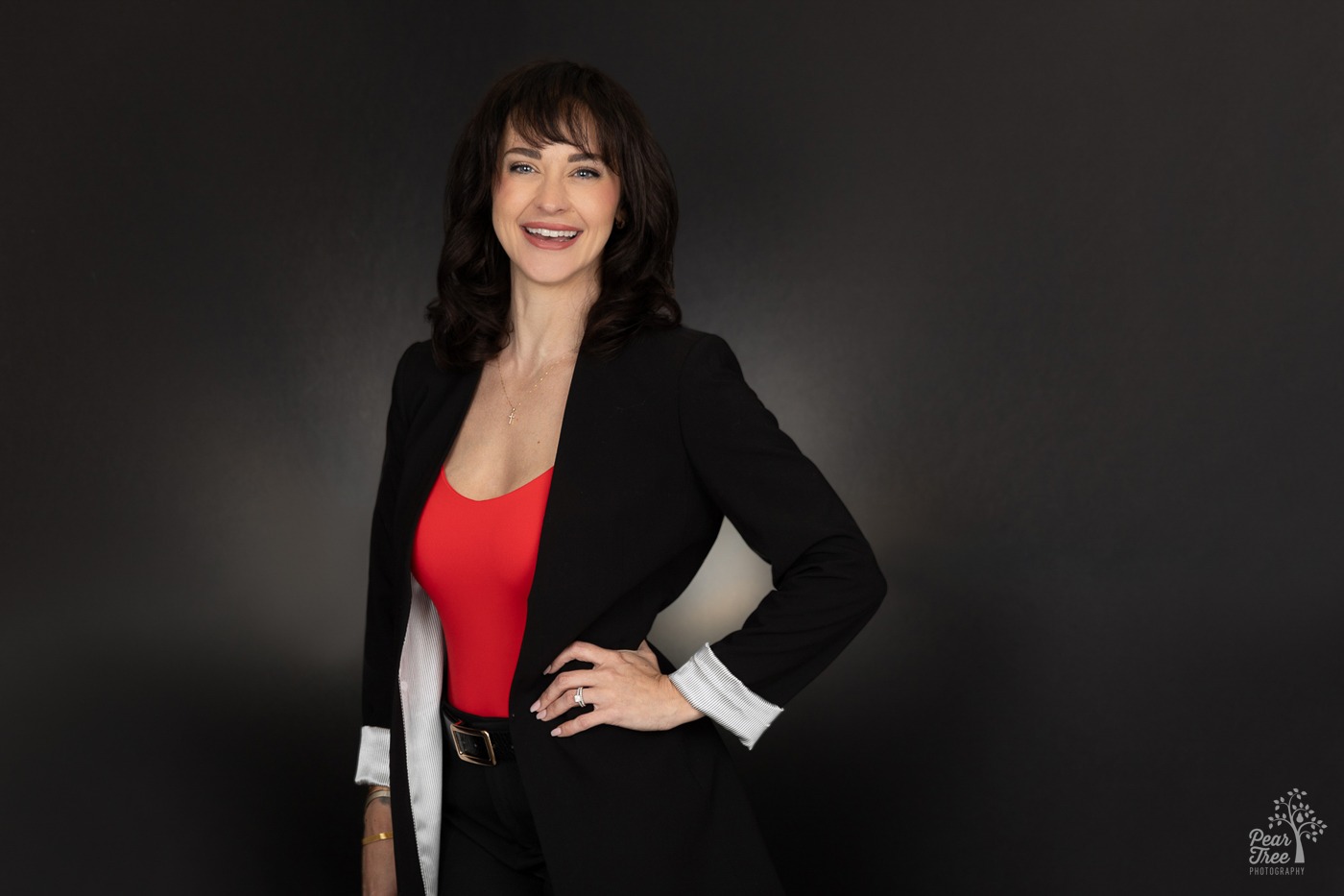 Keller Williams Realtor Meagan Farrow smiling in a black suit with a red cami in a Kennesaw photographer's studio