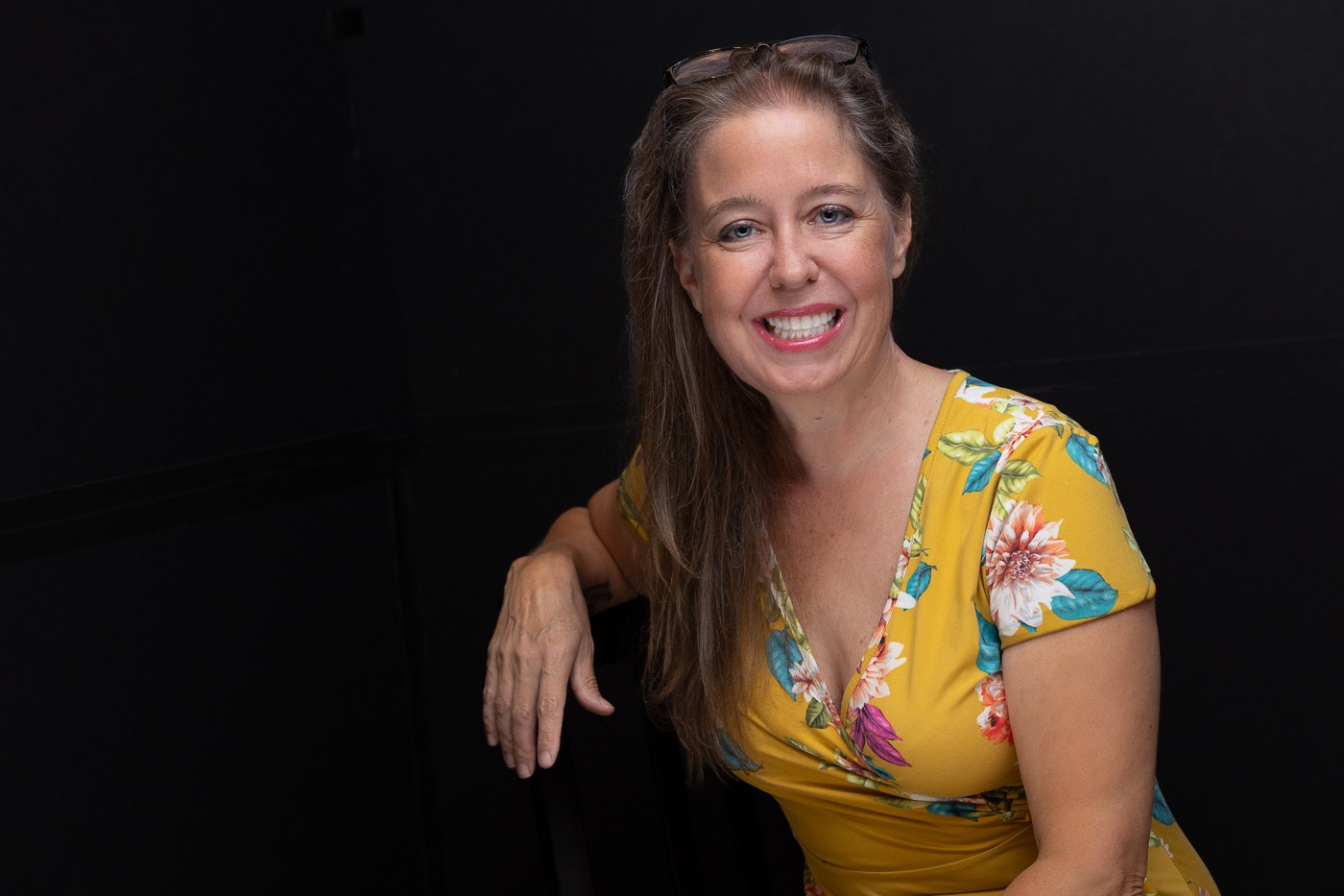 Professional headshot of Kennesaw photographer in a yellow dress with a dark background