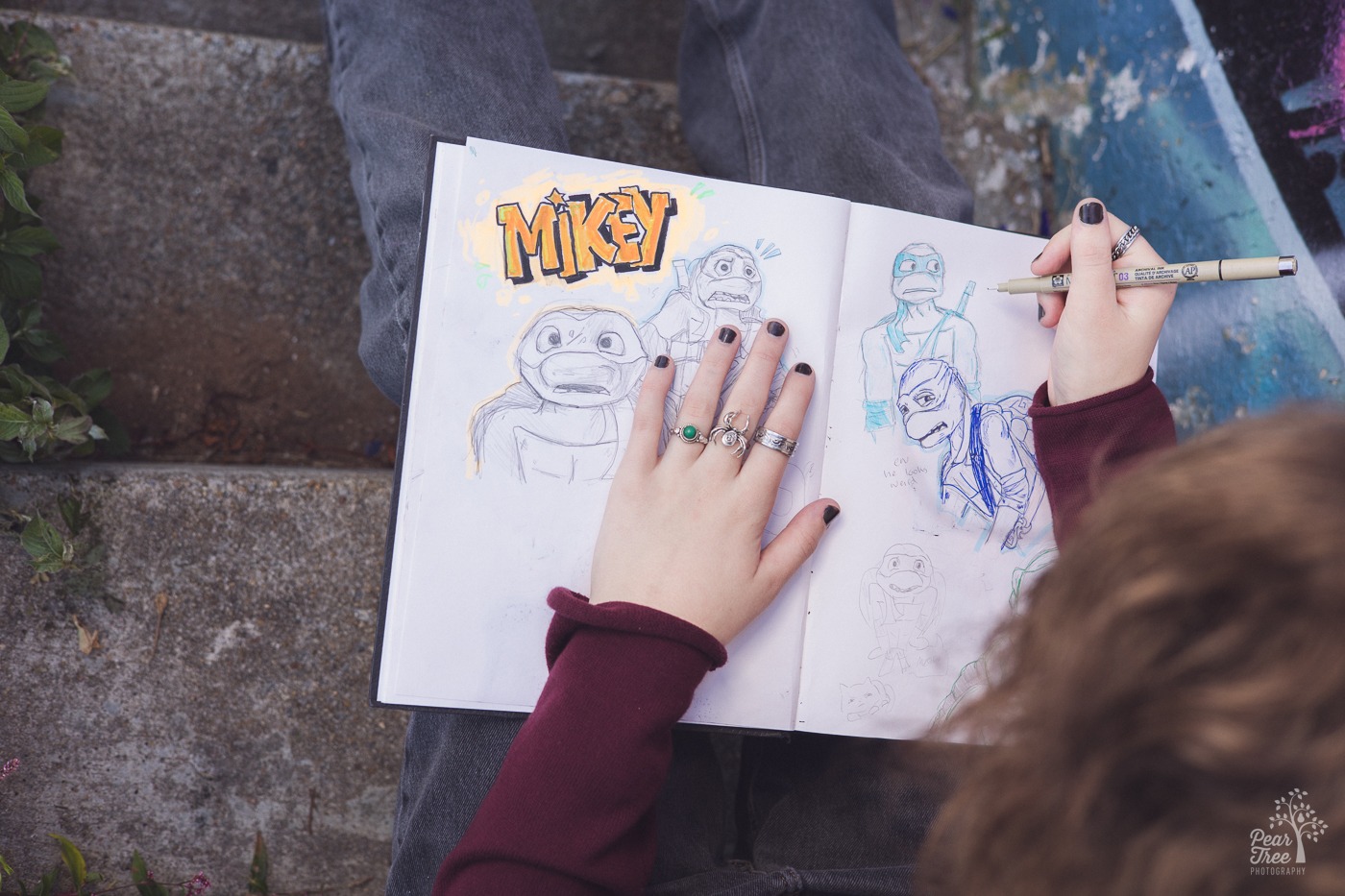 Sketch book with Teenage Mutant Ninja Turtle drawings covered by artist hands