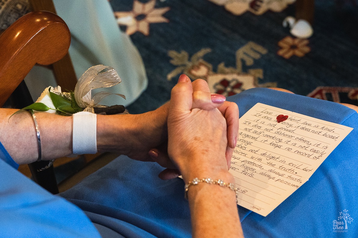 Mother of the groom clasping her hands in her lap over Corinthians 13:4-8 handwritten note card