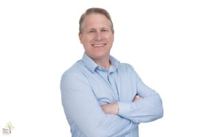 Professional headshot of a man in Kennesaw wearing a blue shirt and smiling in front of a white background