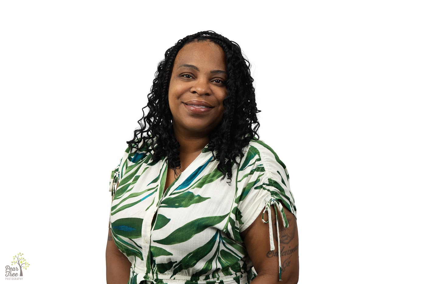 Smiling African-American woman with curled hair wearing a white and green dress
