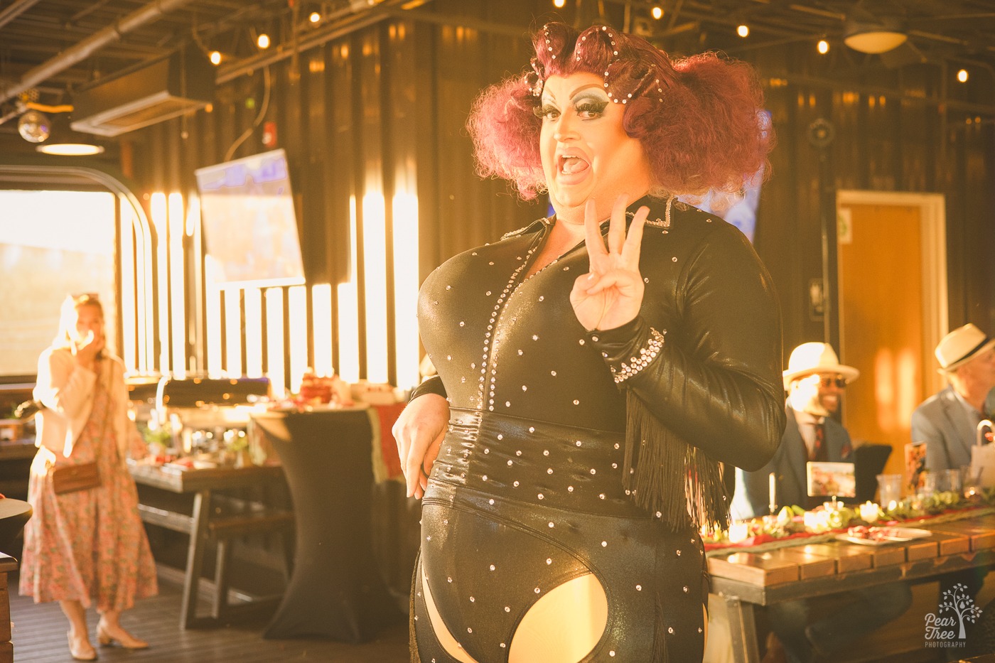 Atlanta drag queen Tugboat singing looking stunning while holding up three fingers with a song