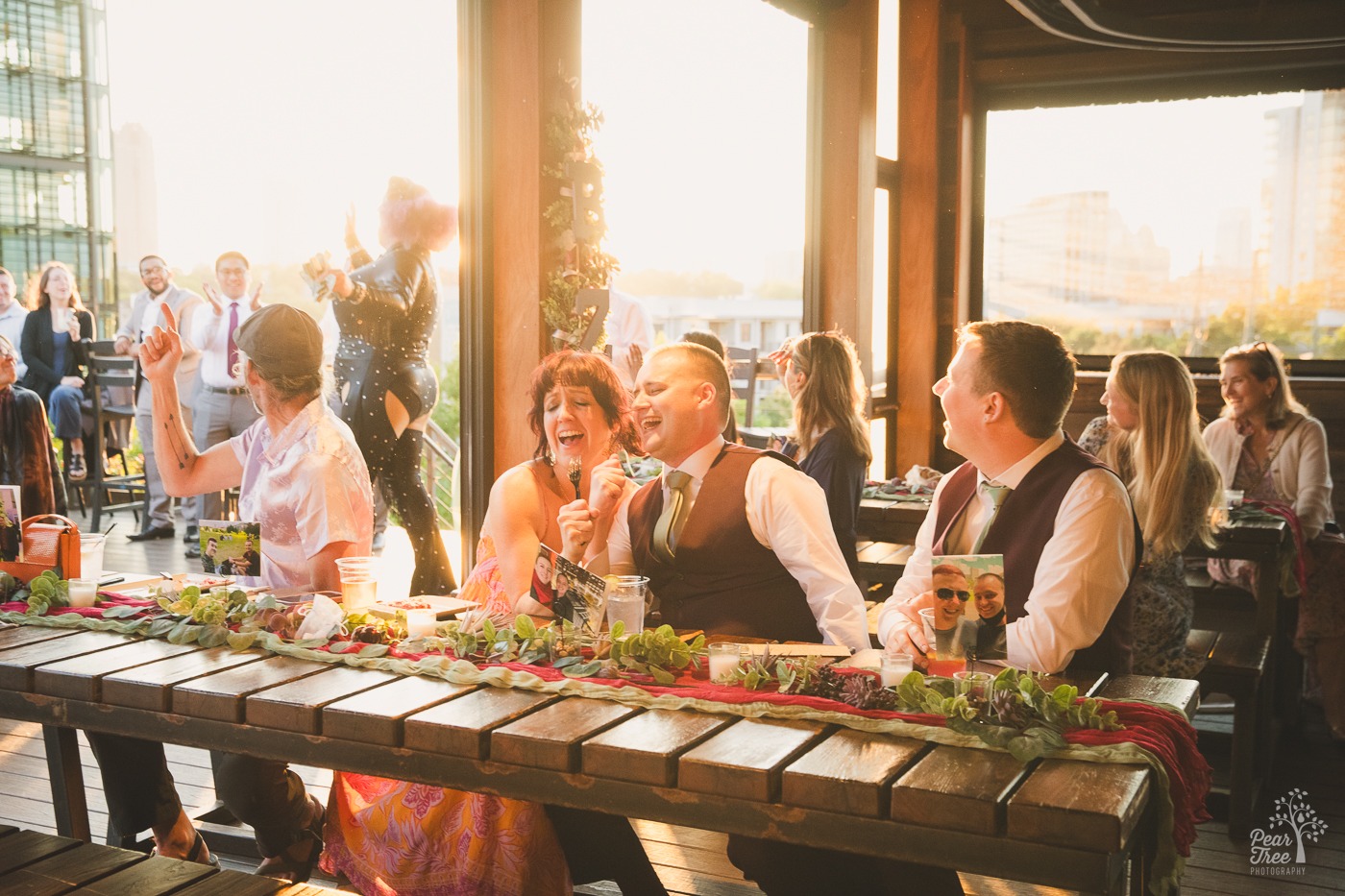 Grooms laughing and singing to forks with a friend during drag queen performance at New Realm Brewing Co.