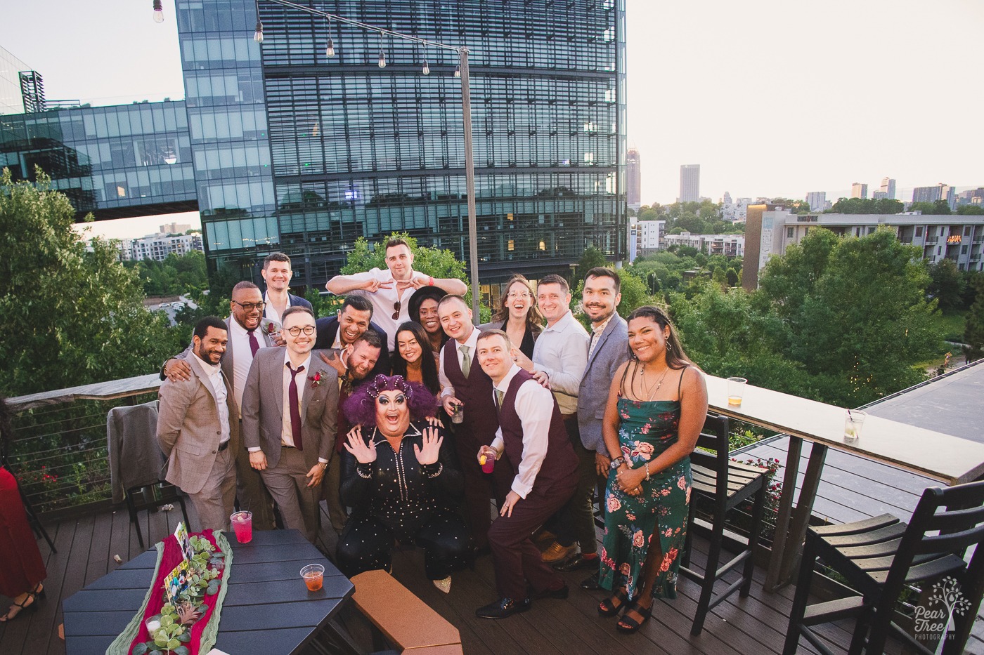 Wedding party posing with Atlanta drag queen Tugboat on New Realm Brewing Co rooftop deck with Atlanta skyline in background