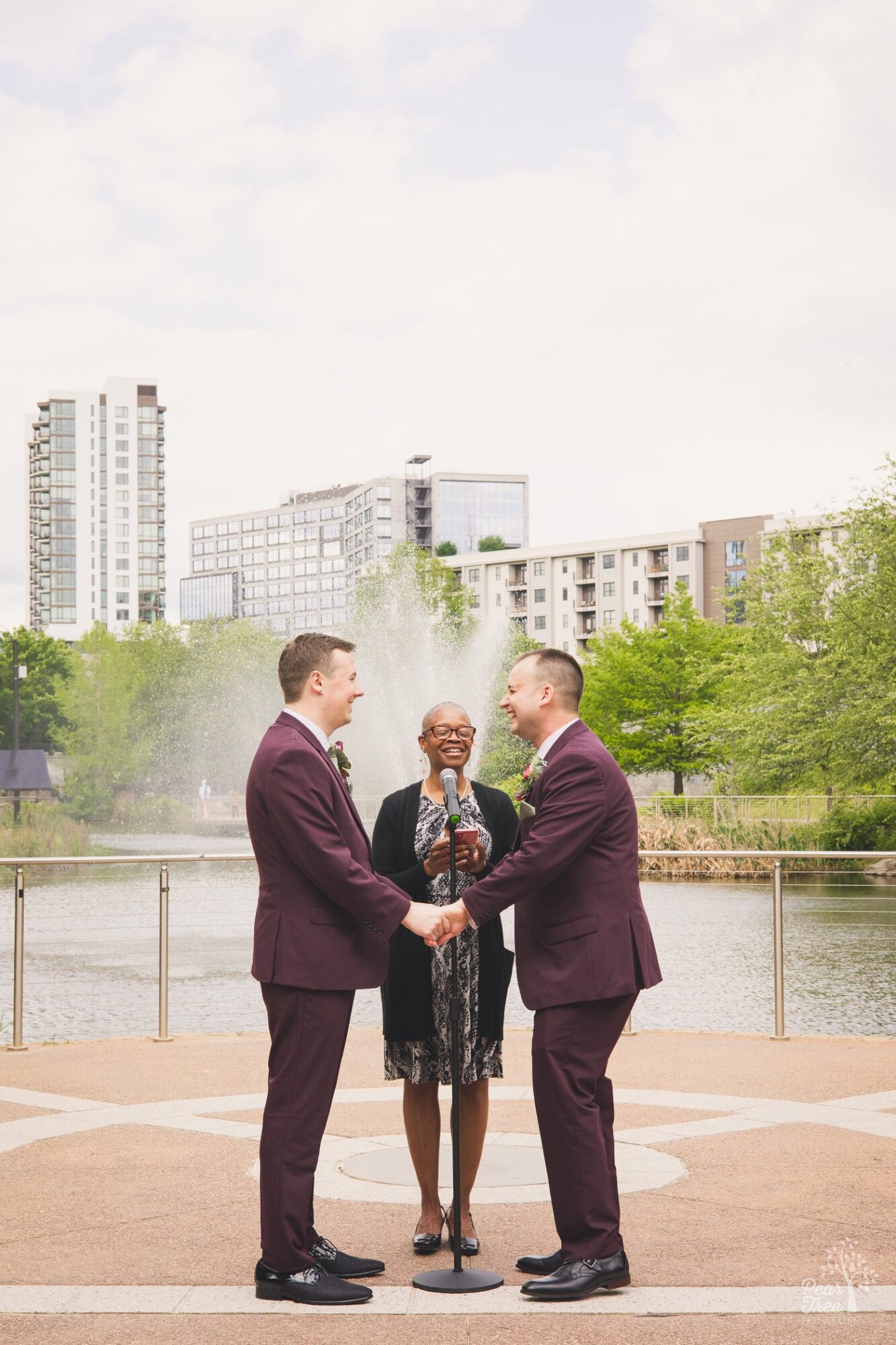 Two grooms laughing and holding hands during Old 4th Ward wedding ceremony