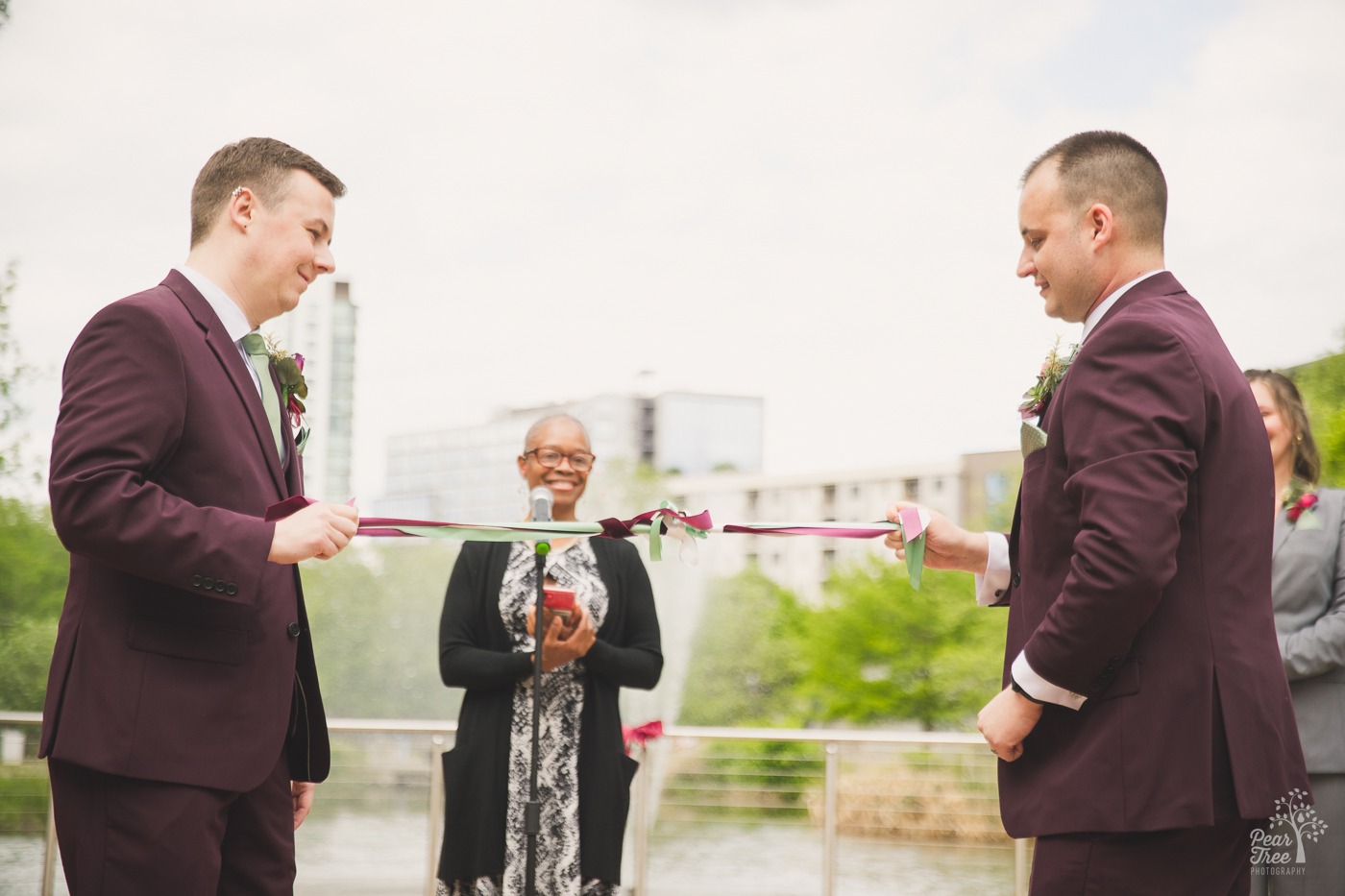 Two grooms tying the knot in a hand fasting ceremony at their Old 4th Ward wedding