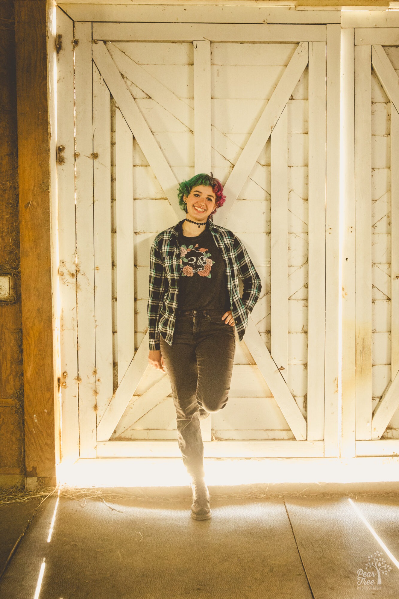 Adairsville high school senior leaning against a barn door with sunlight shining in around her