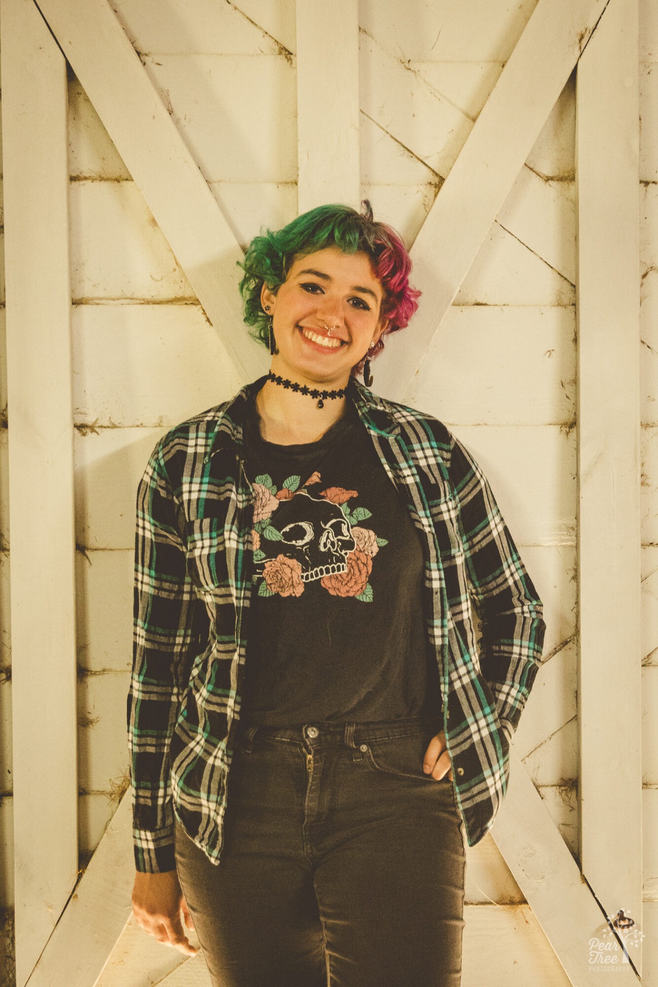 Smiling high school senior leaning against a white barn door