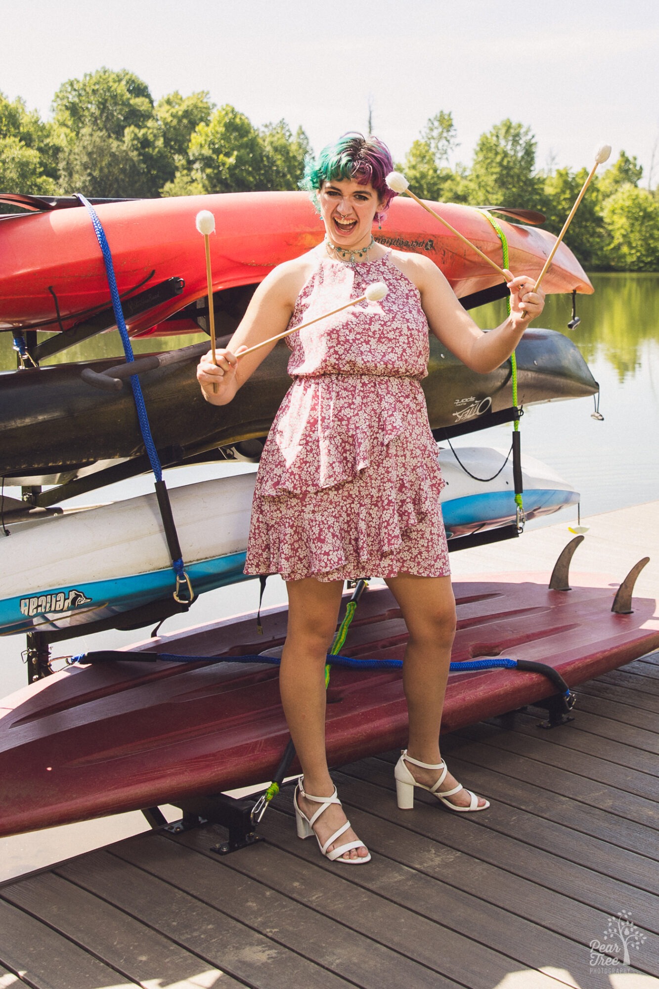 Adairsville high school senior standing in front of her family's kayaks and waving her percussion sticks from band