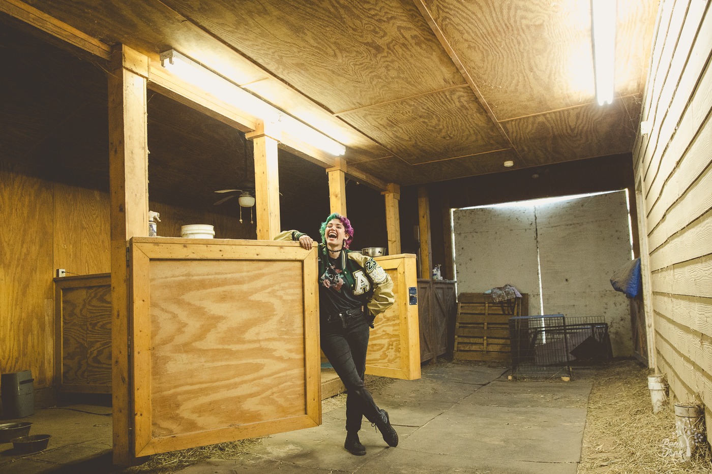 Adairsville high school senior wearing her letterman jacket and laughing inside the alpaca barn where she works